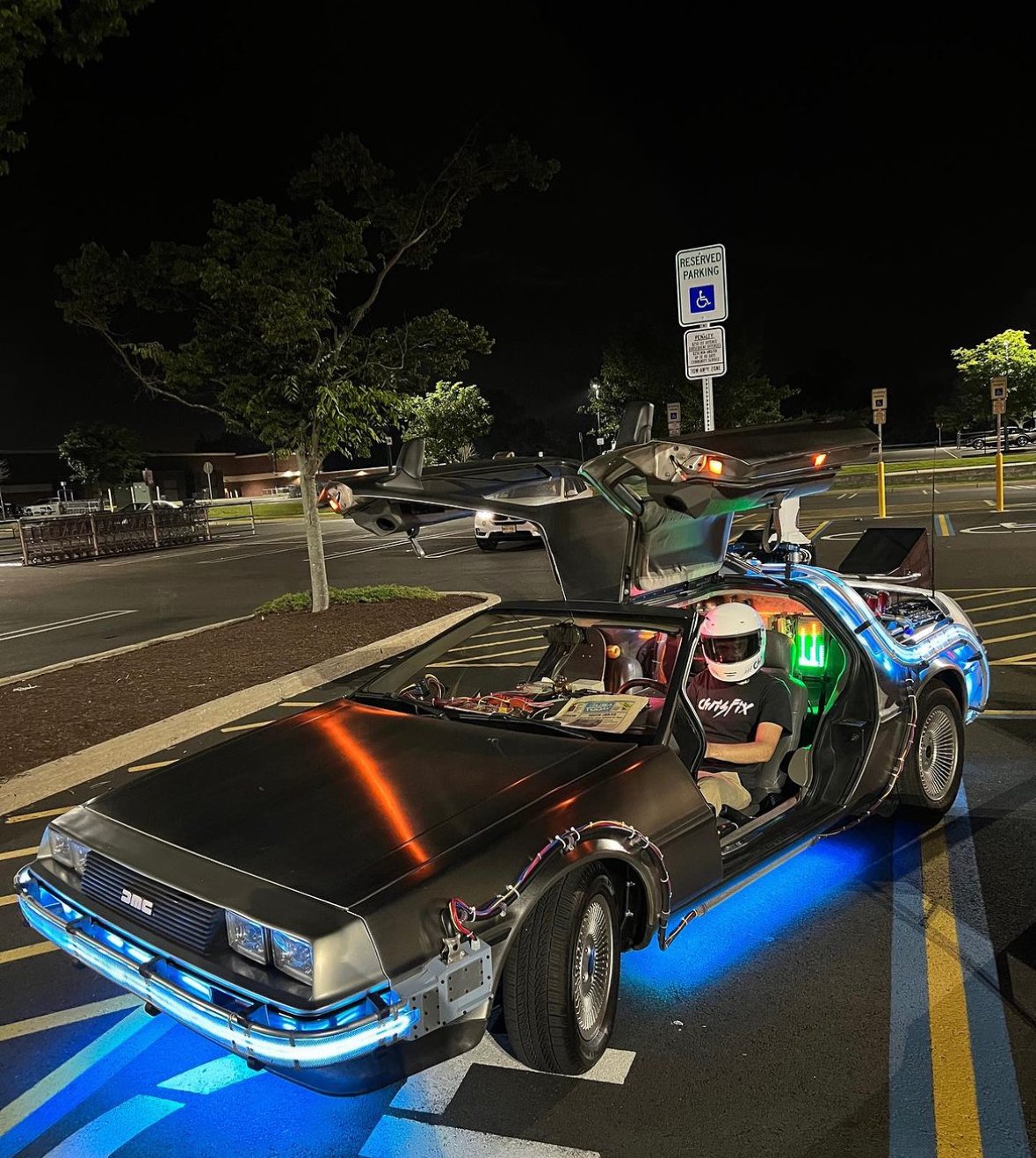DeLorean Time Machine with gull-wing doors open at night, blue underglow