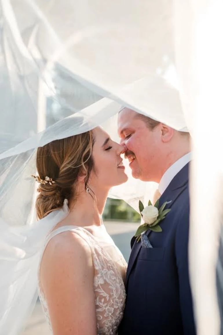 Bride and groom kissing under veil by The Pretty Agency
