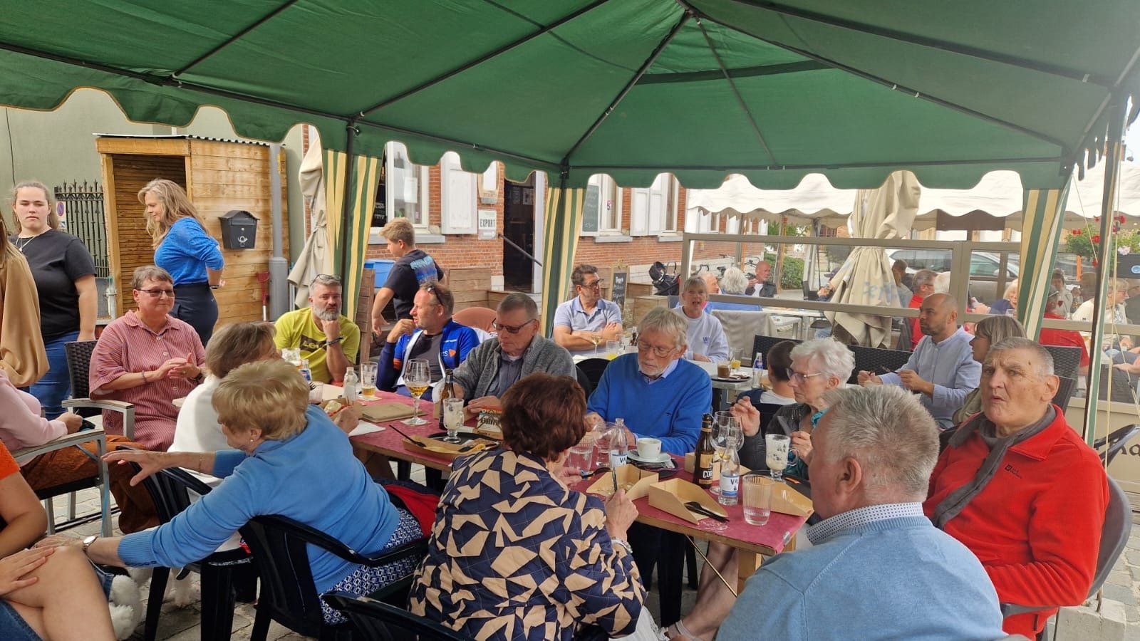Grote groep gasten tafelt samen — catering onder tent