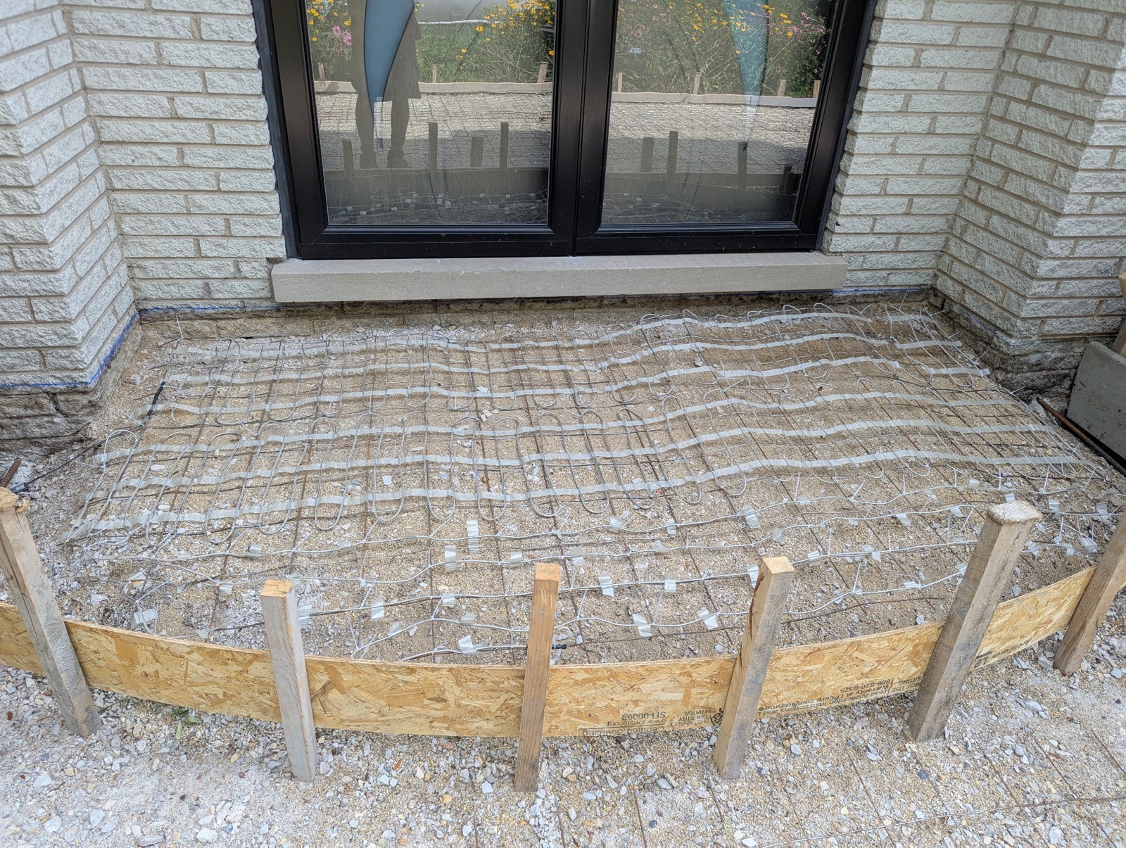 Heated patio floor installation — heating cables on rebar mesh before concrete pour near home entrance