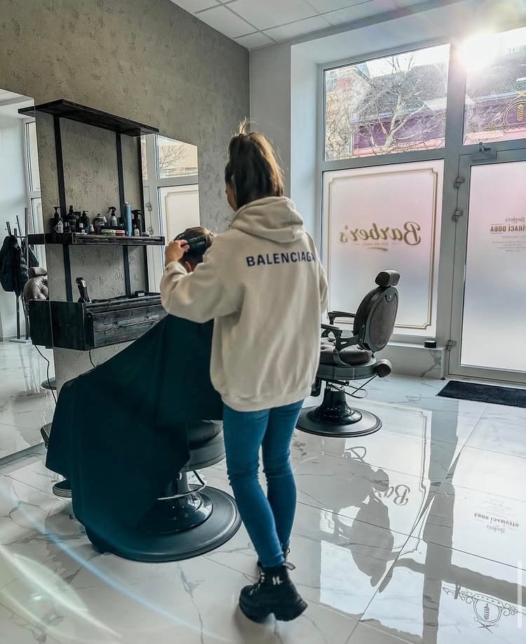 Barberka stříhající zákazníkovi vlasy v holičství Barber's Hodonín