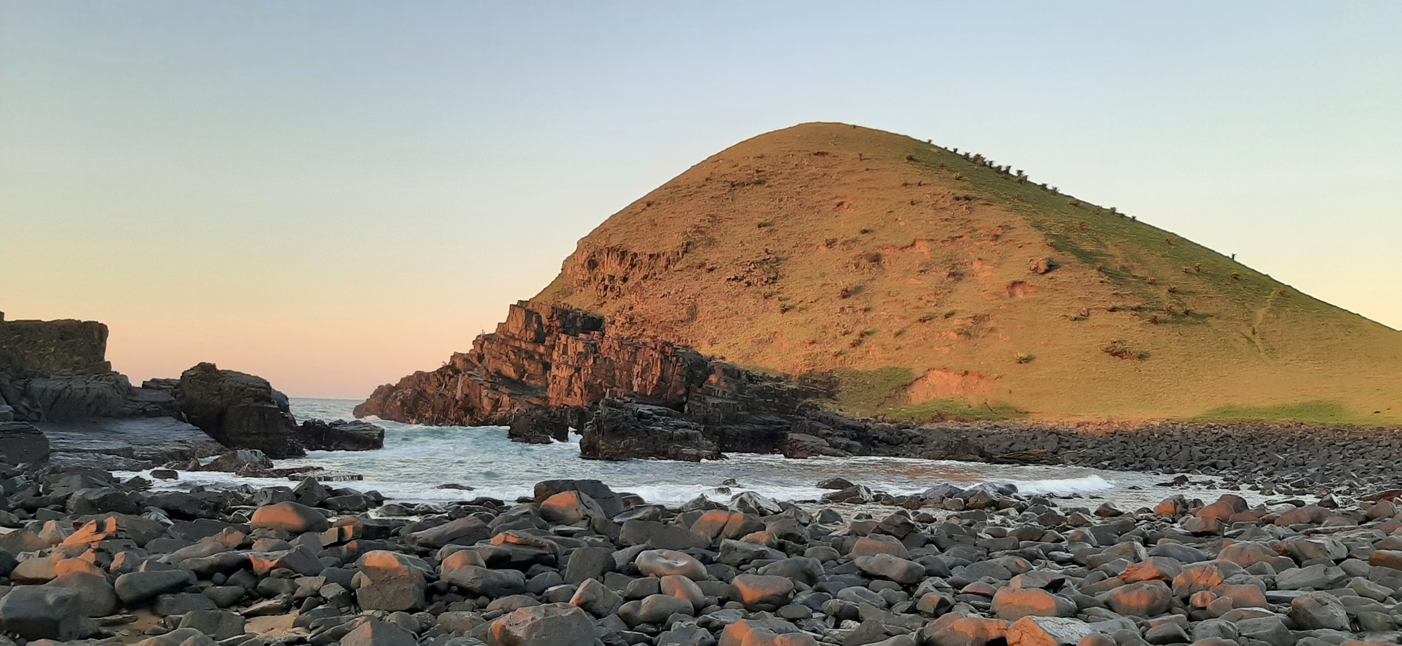The dramatic green headland at the edge of the cove