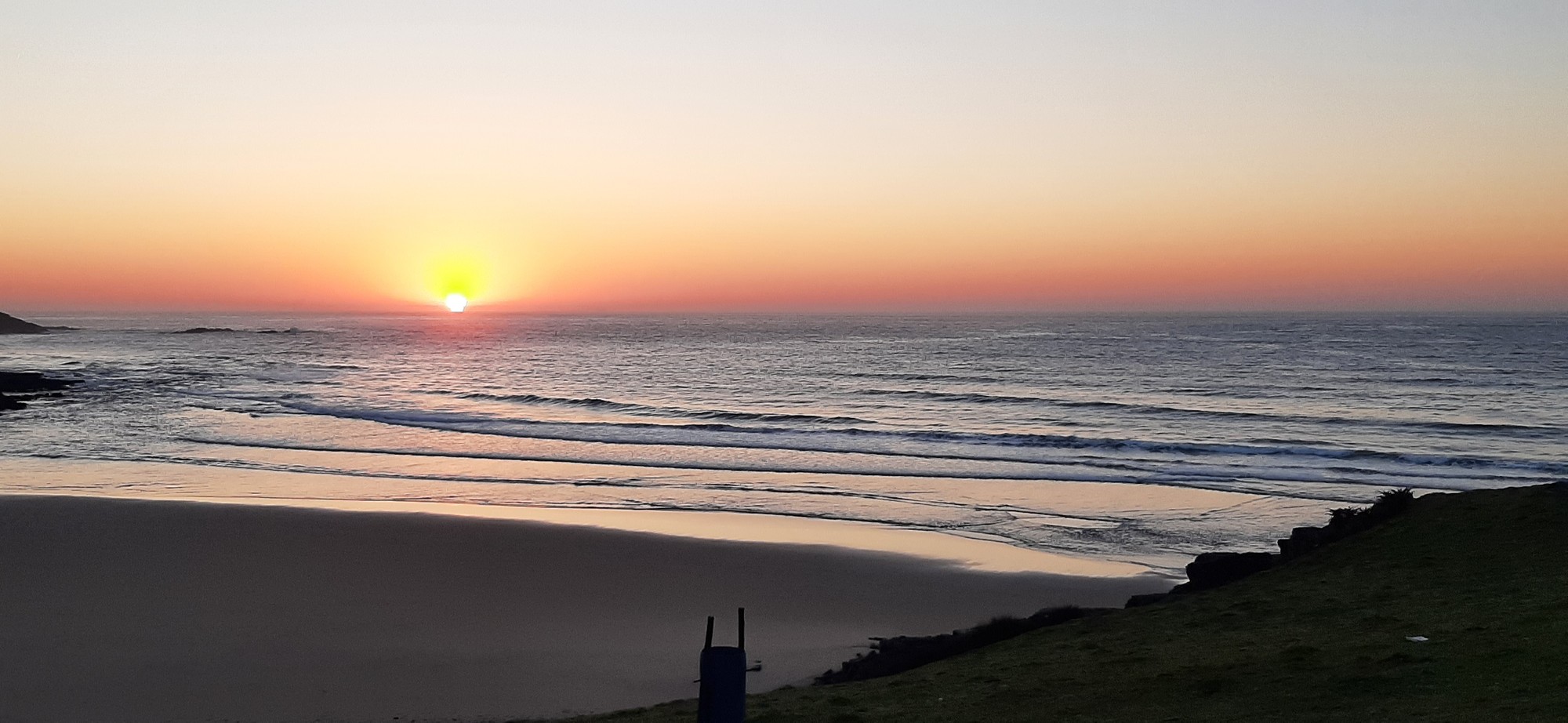Golden sunrise breaking over the wide sandy beach
