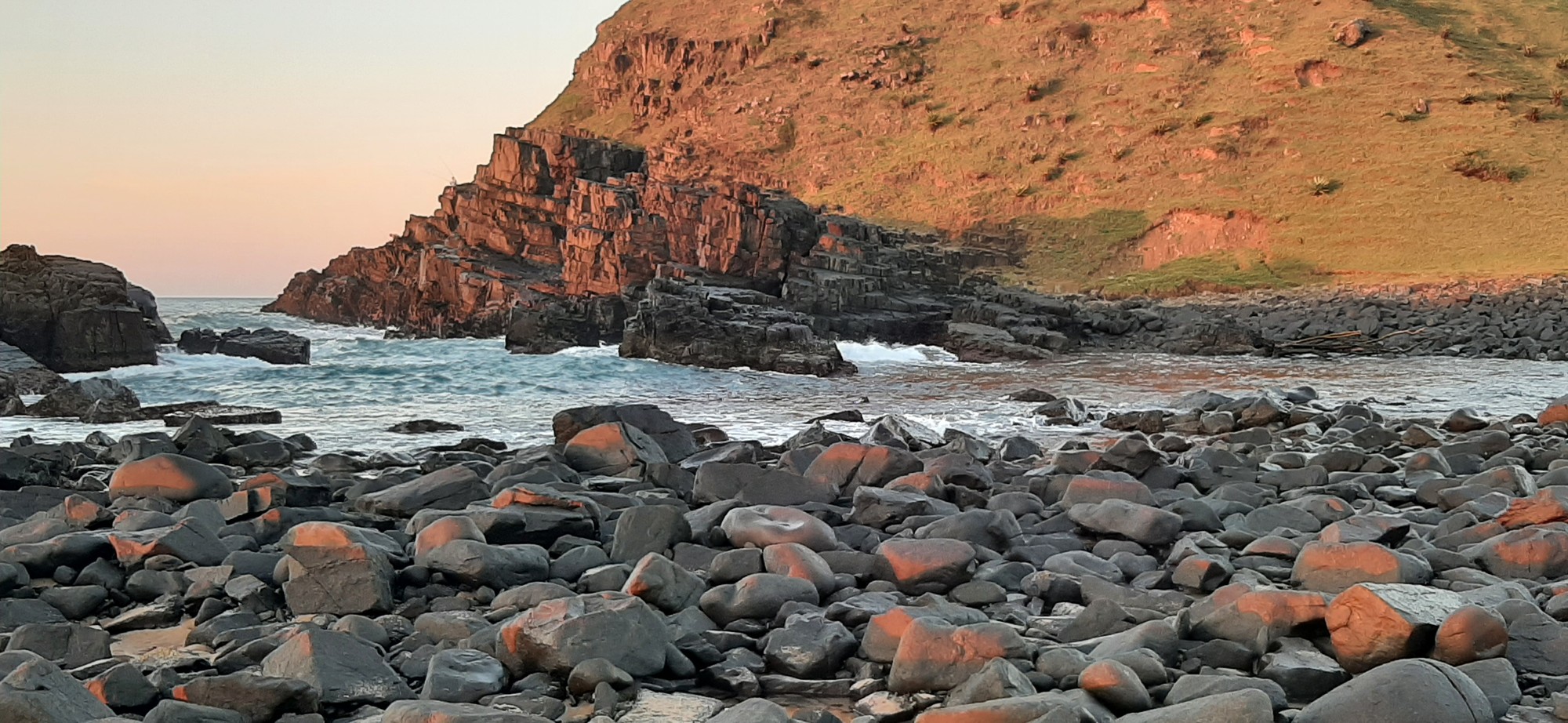 Glowing red cliffs and rocks lit by the first light of dawn