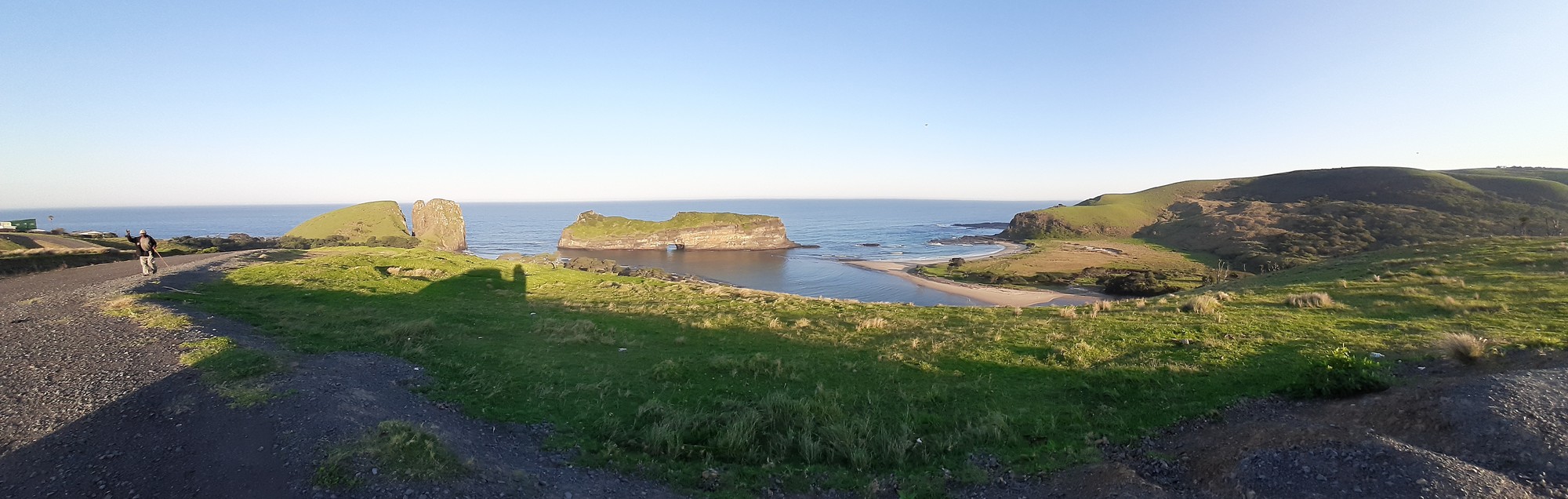 Wide panorama of Hole in the Wall — island, lagoon, and rolling green hills