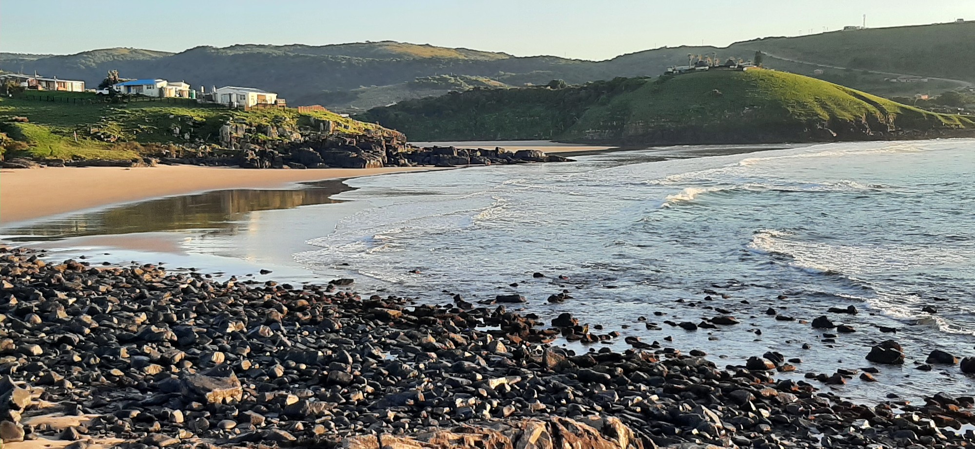 Morning light catches the golden arc of the cove beach
