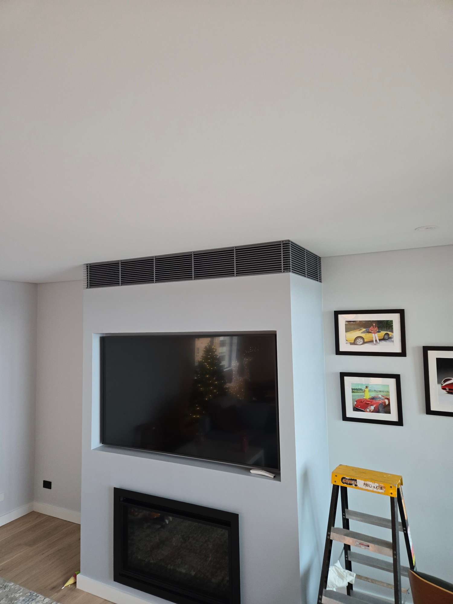 Grey linear slot grille above TV and fireplace entertainment unit