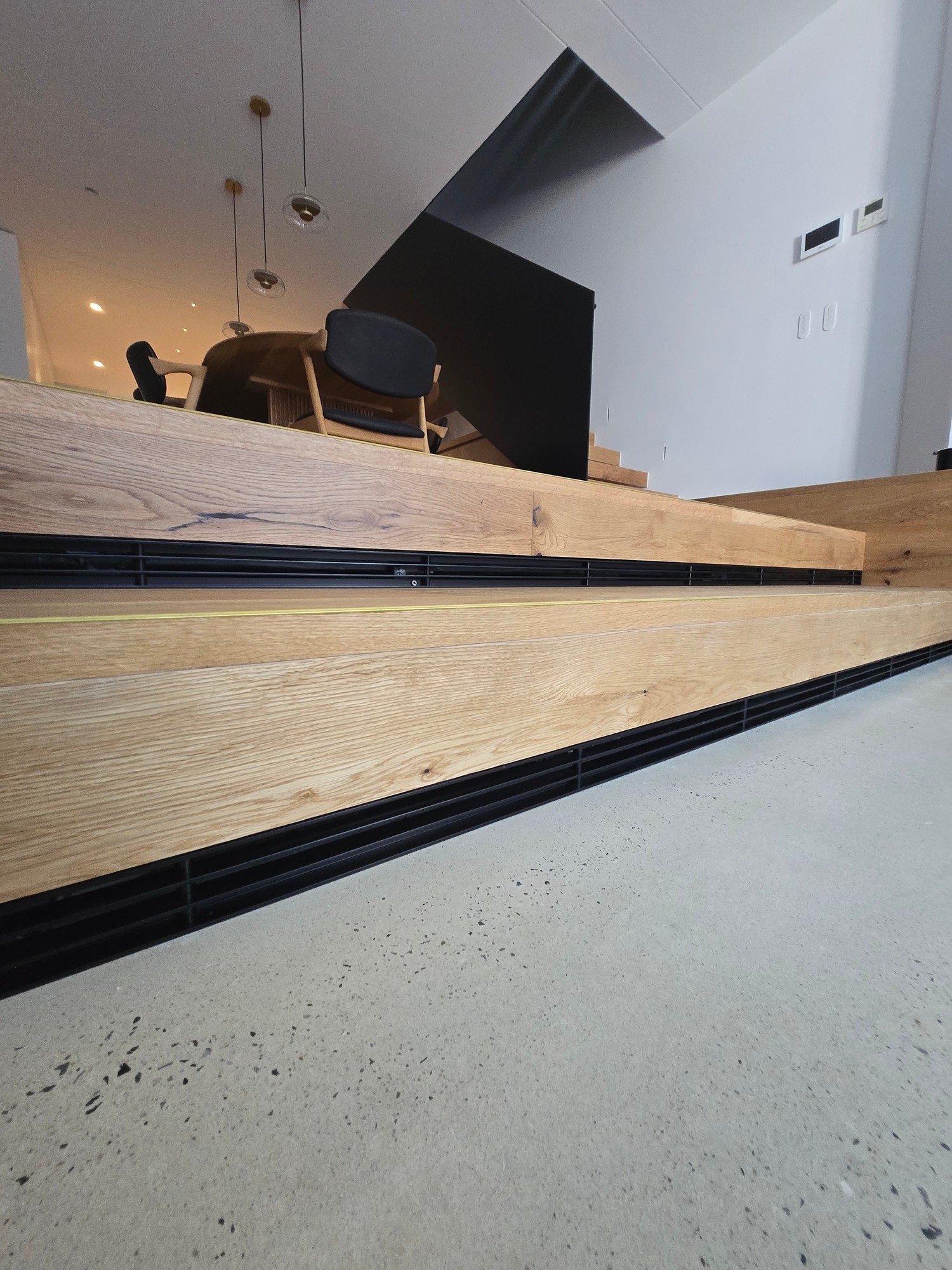Black linear slot grilles integrated under timber stair risers