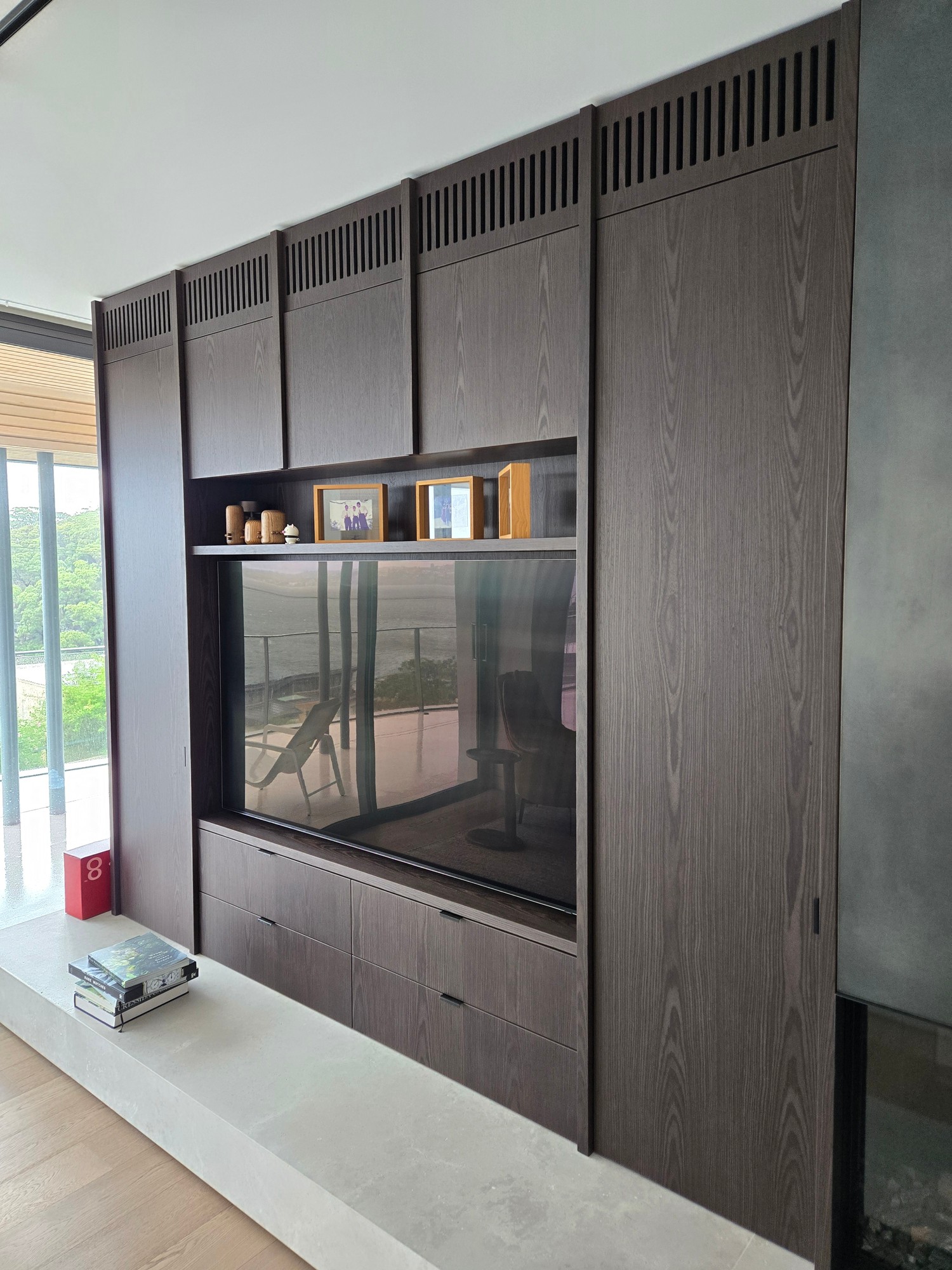 Slatted architectural grilles integrated into dark timber media joinery