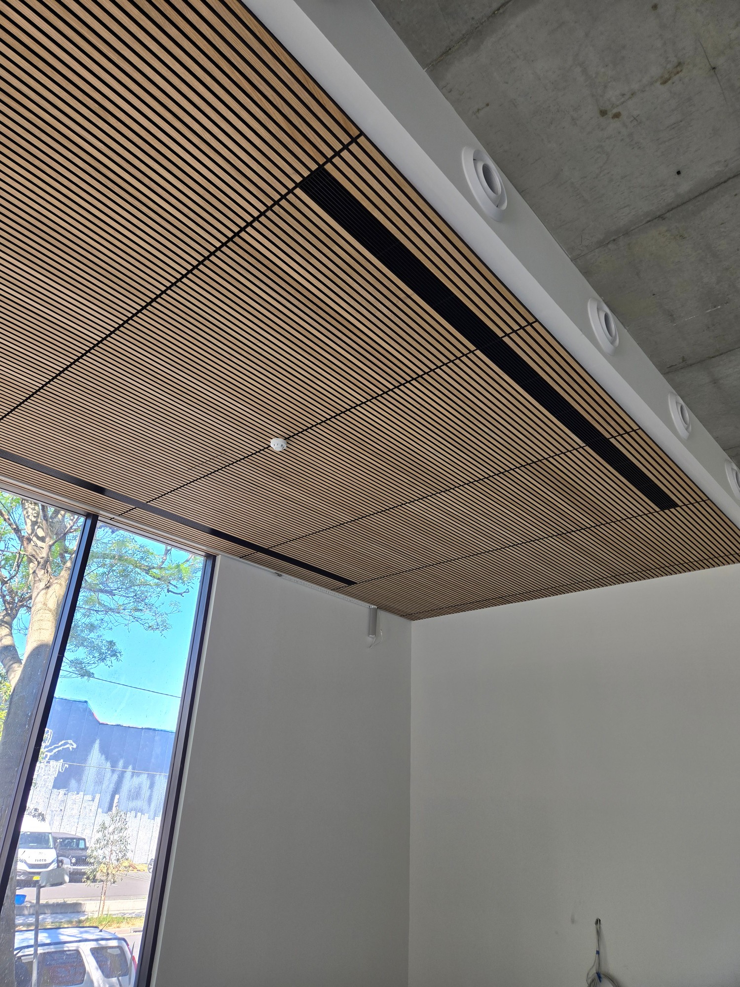 Black linear grilles concealed within a timber battened ceiling