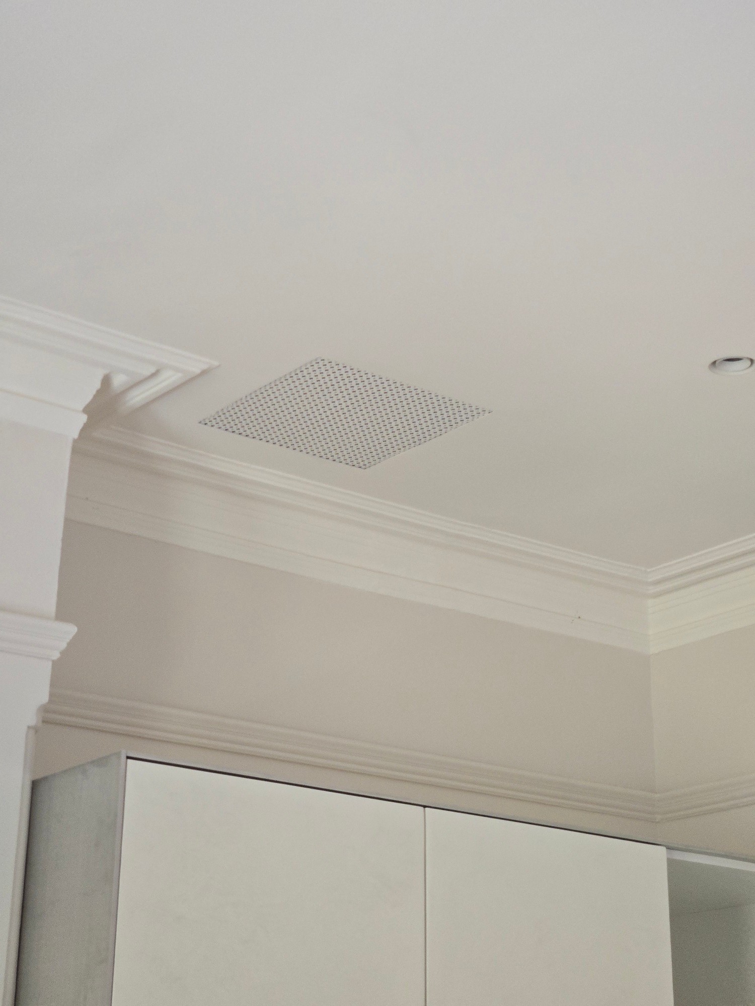 Perforated square grille flush-mounted in ornate traditional plastered ceiling