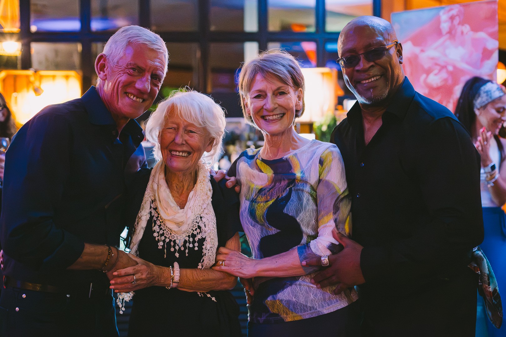 An older dancer in a black dress holding hands with her partner on the dance floor