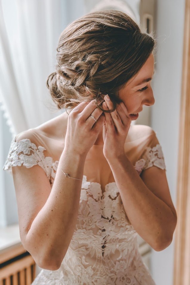 Bruid met opgestoken kapsel en bloemen tijdens haar voorbereidingen