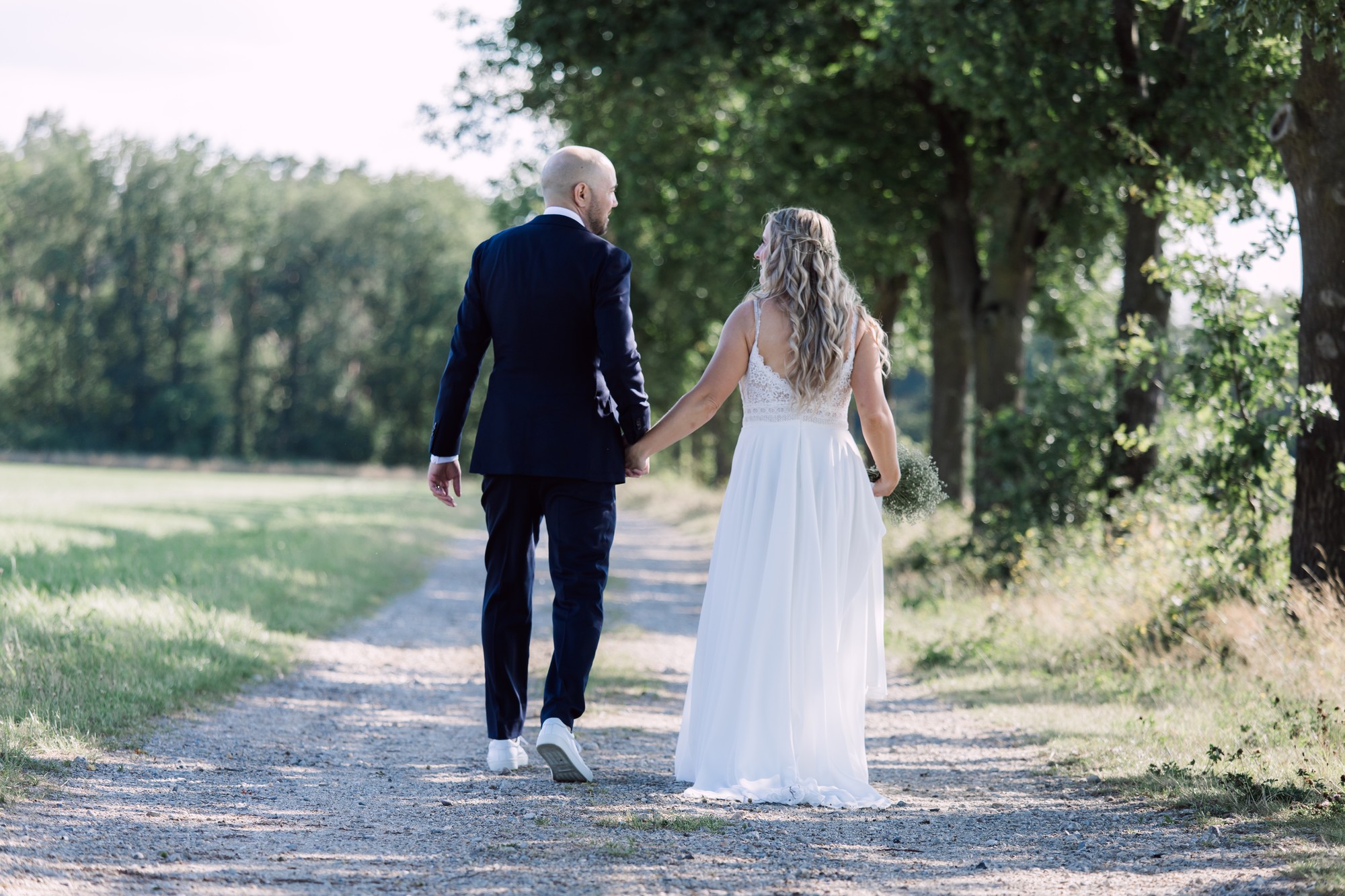 Bruidspaar wandelend door een groene laan