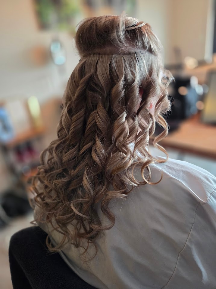 Bruidskapsel met clip-in extensions in lange, losse krullen tijdens de voorbereiding