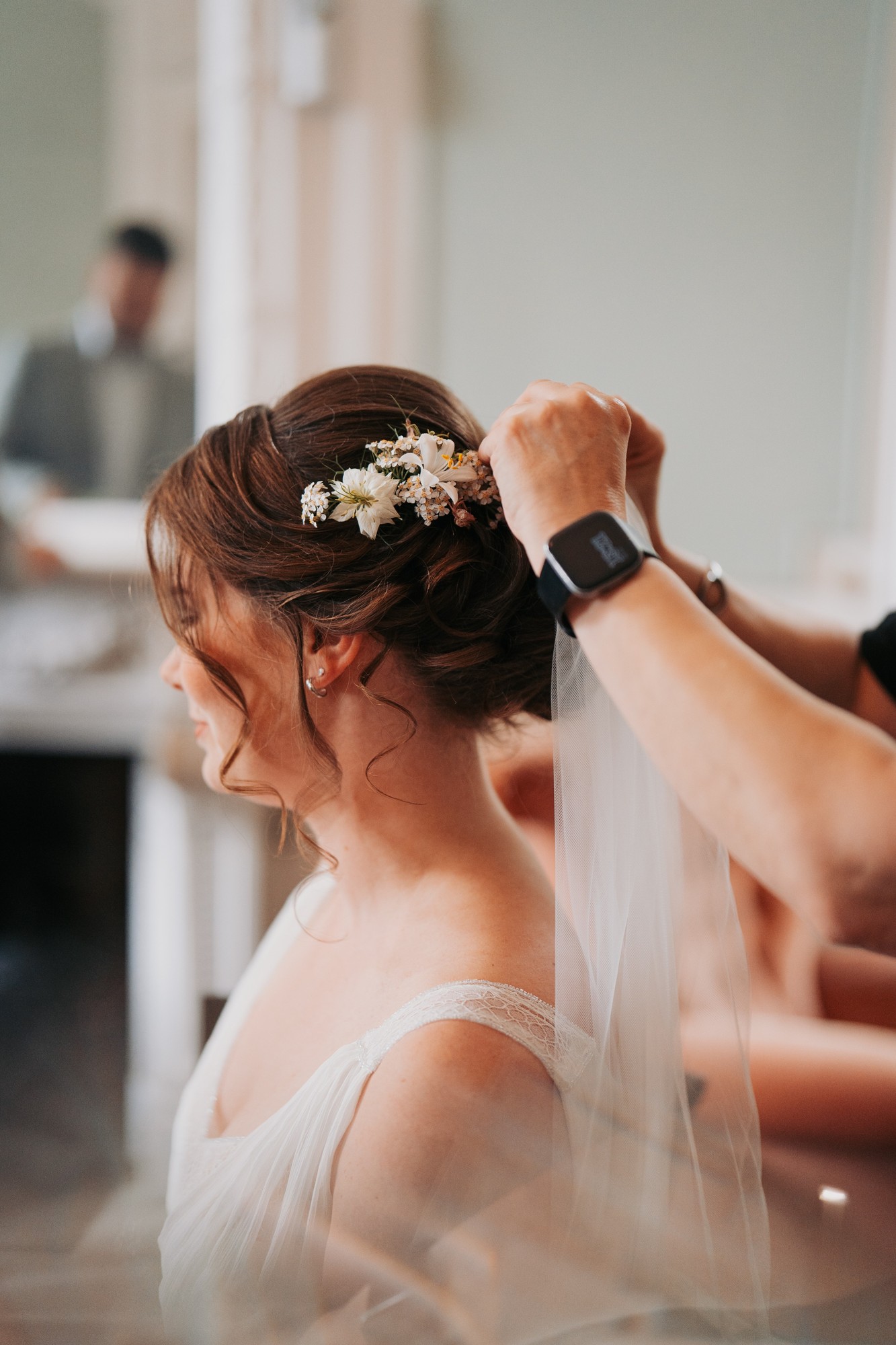 Close-up van het inwerken van bloemen in een opgestoken kapsel met sluier