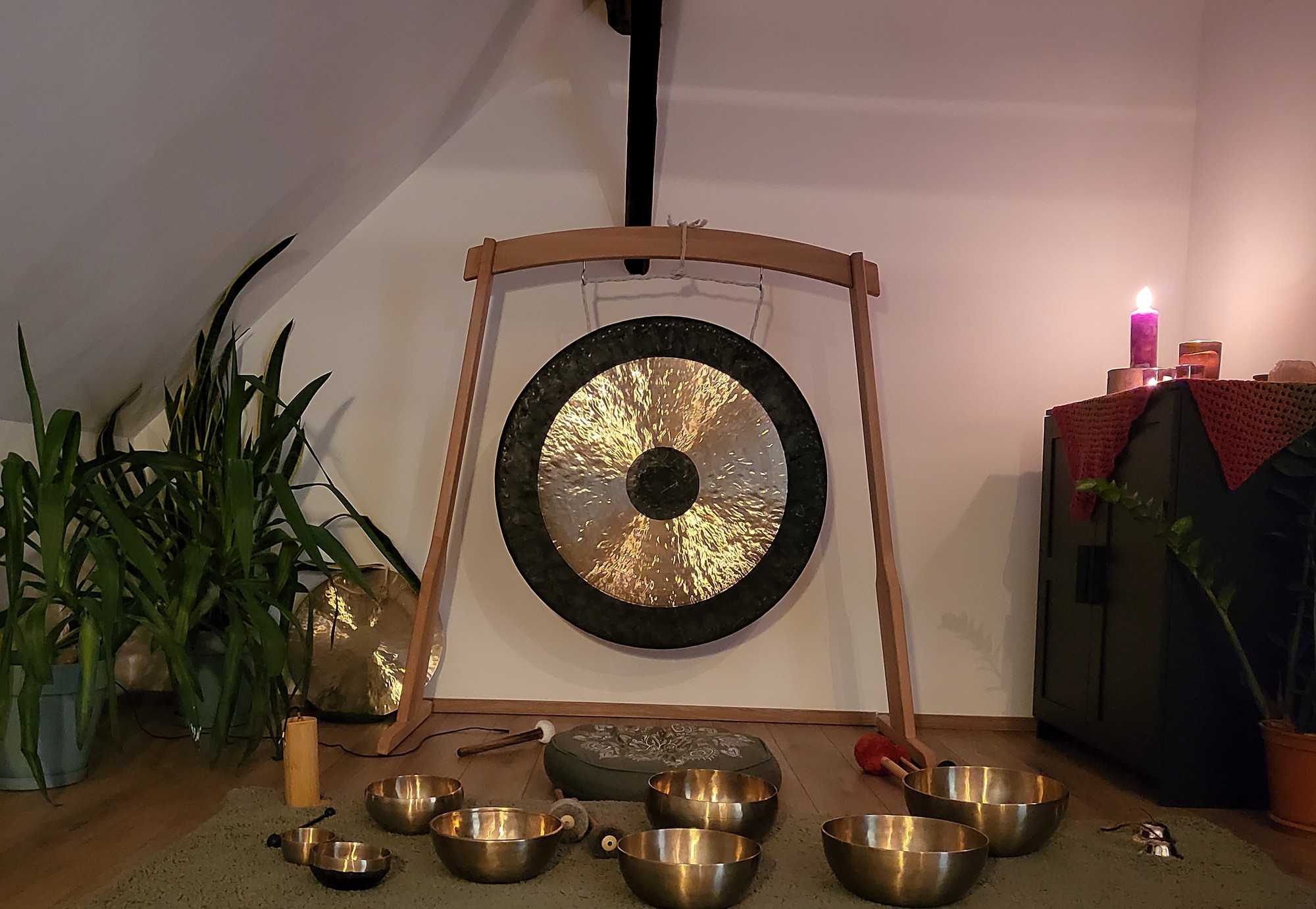 Gong und Klangschalen im Ritualraum, umringt von Pflanzen und Kerzenlicht