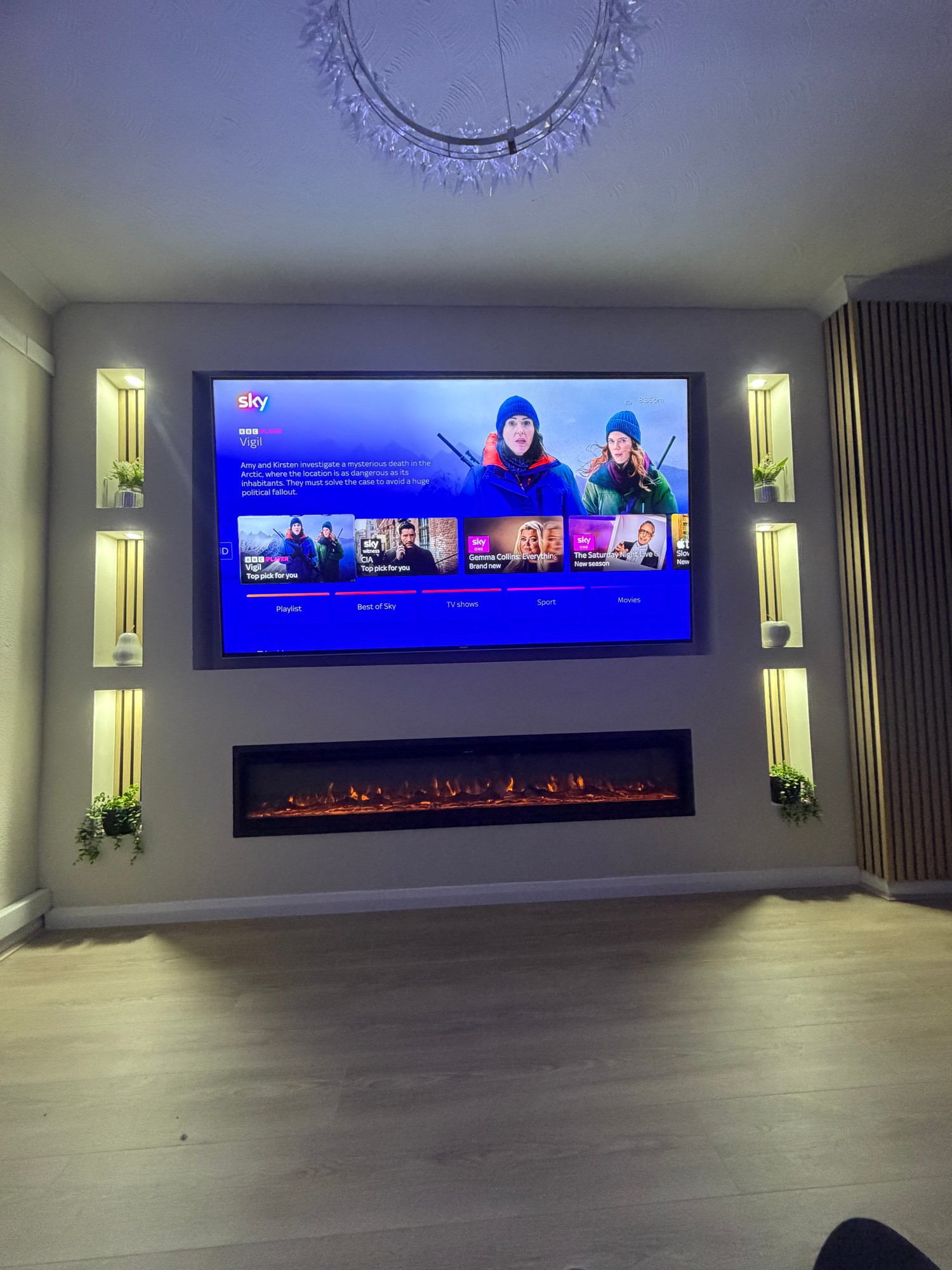 Living room media wall with TV, fireplace and lit shelving