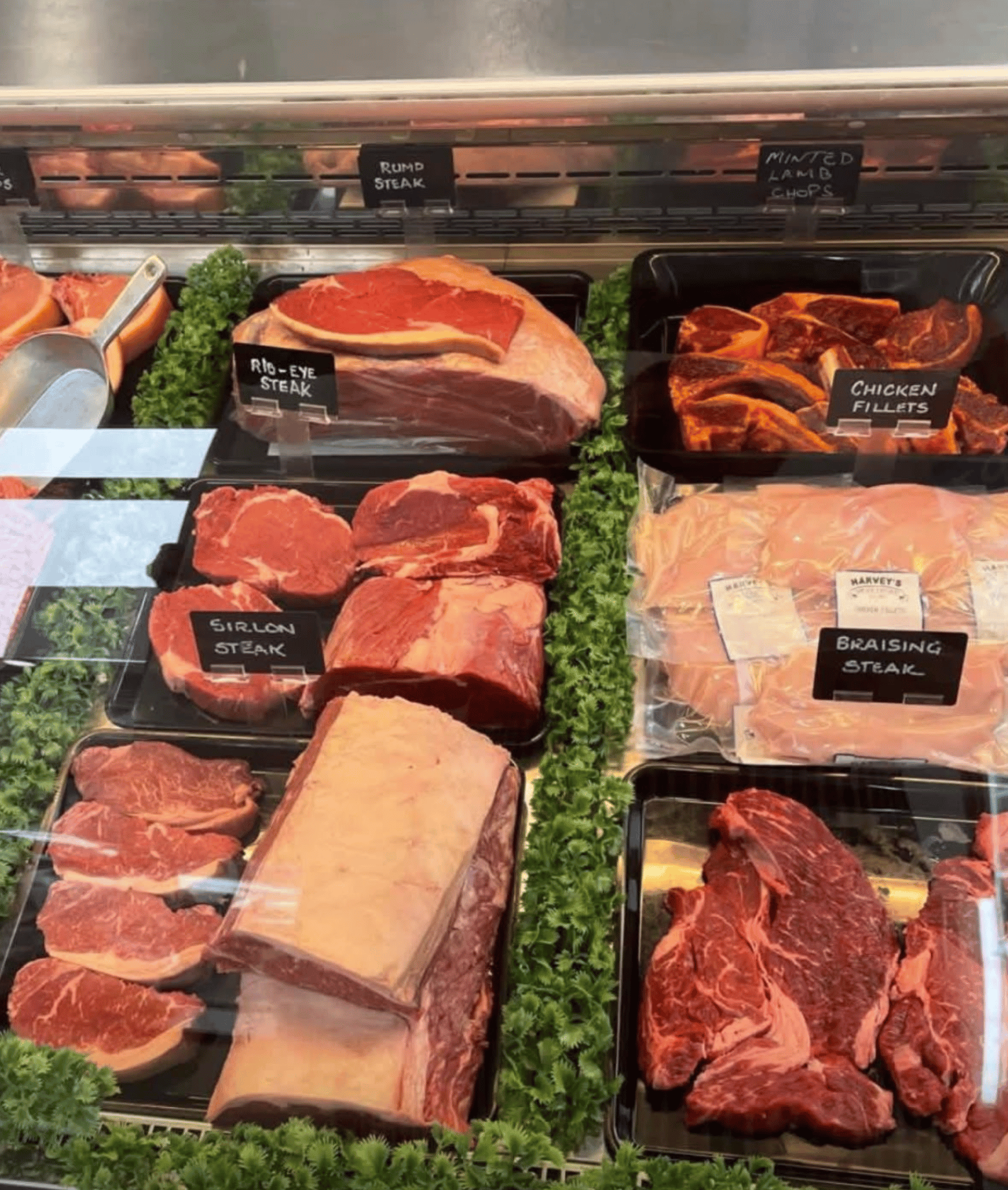 Butcher hanging dry-aged beef and pork in a farm shop display cabinet