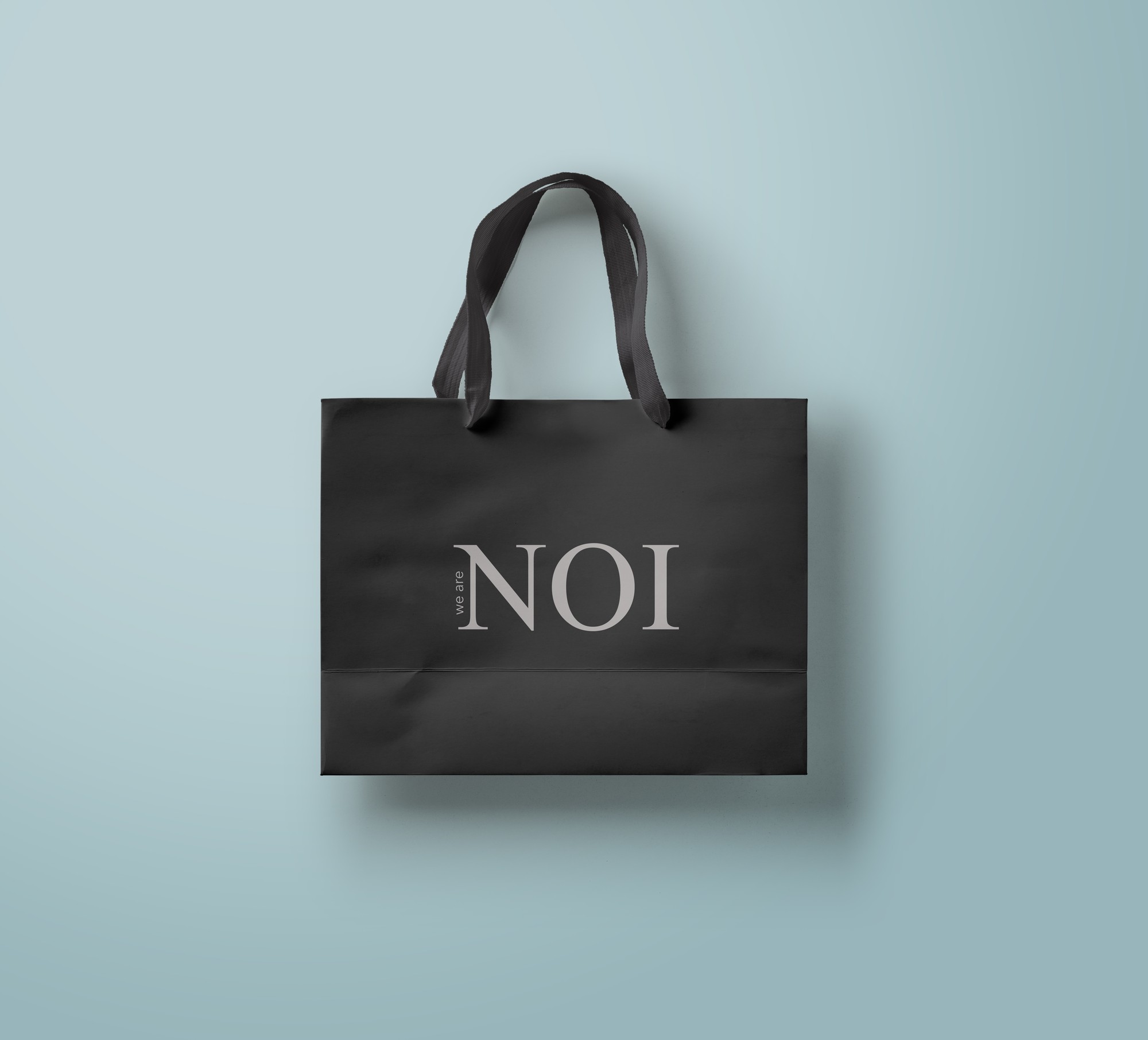 Zwarte papieren draagtas met het we are NOI logo, ontworpen door Studiofraai