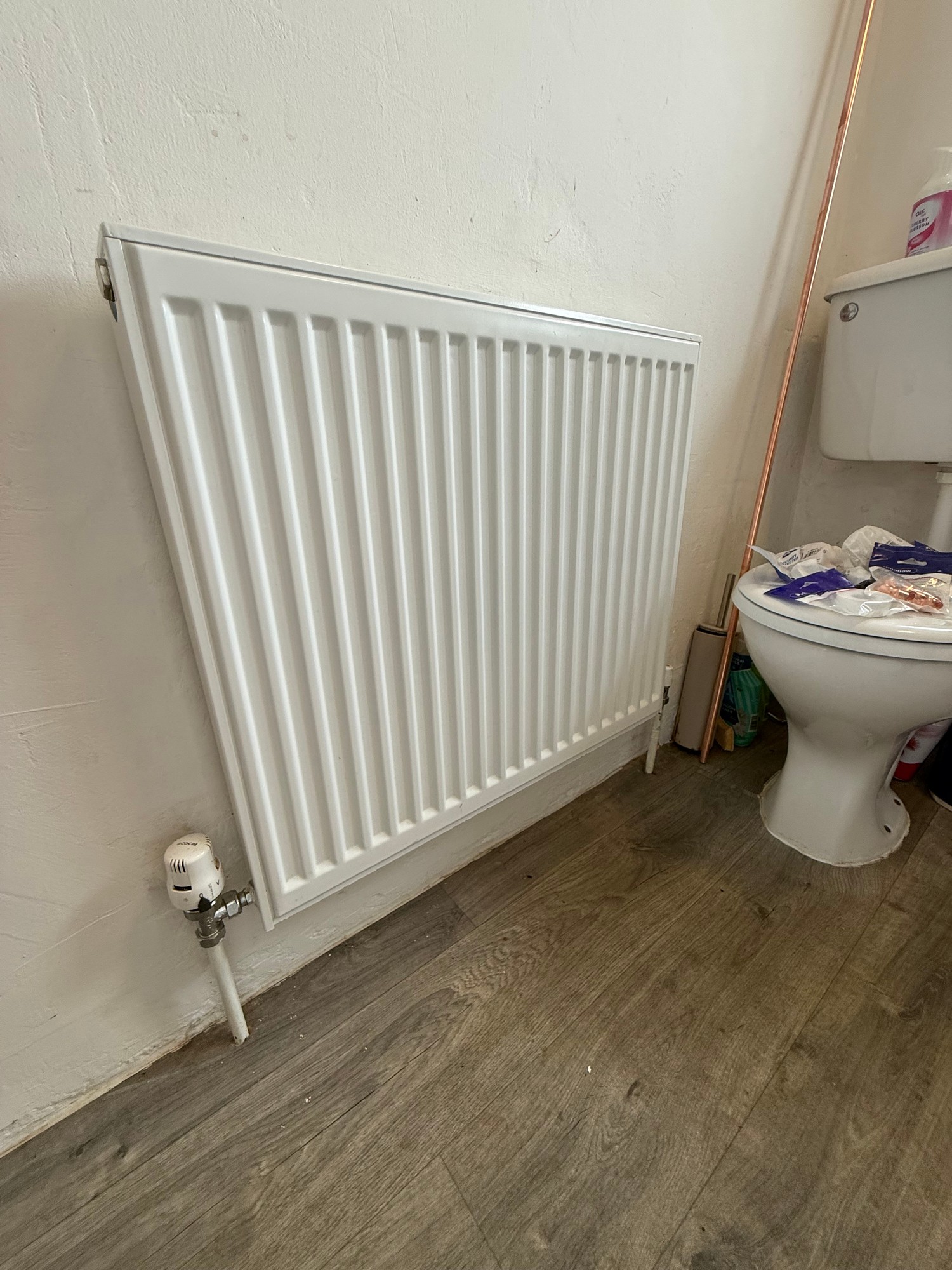 Old white radiator on the wall before a plumbing upgrade