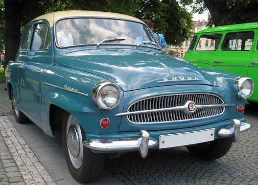 Krémová klasická Škoda Octavia jedoucí po podzimní silnici
