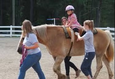 Young rider learning with supportive helpers