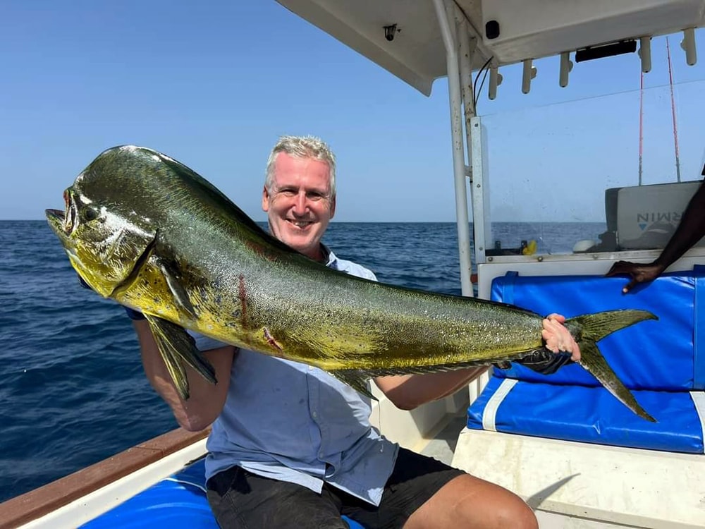 Lystfisker med en imponerende barracuda i blåt hav