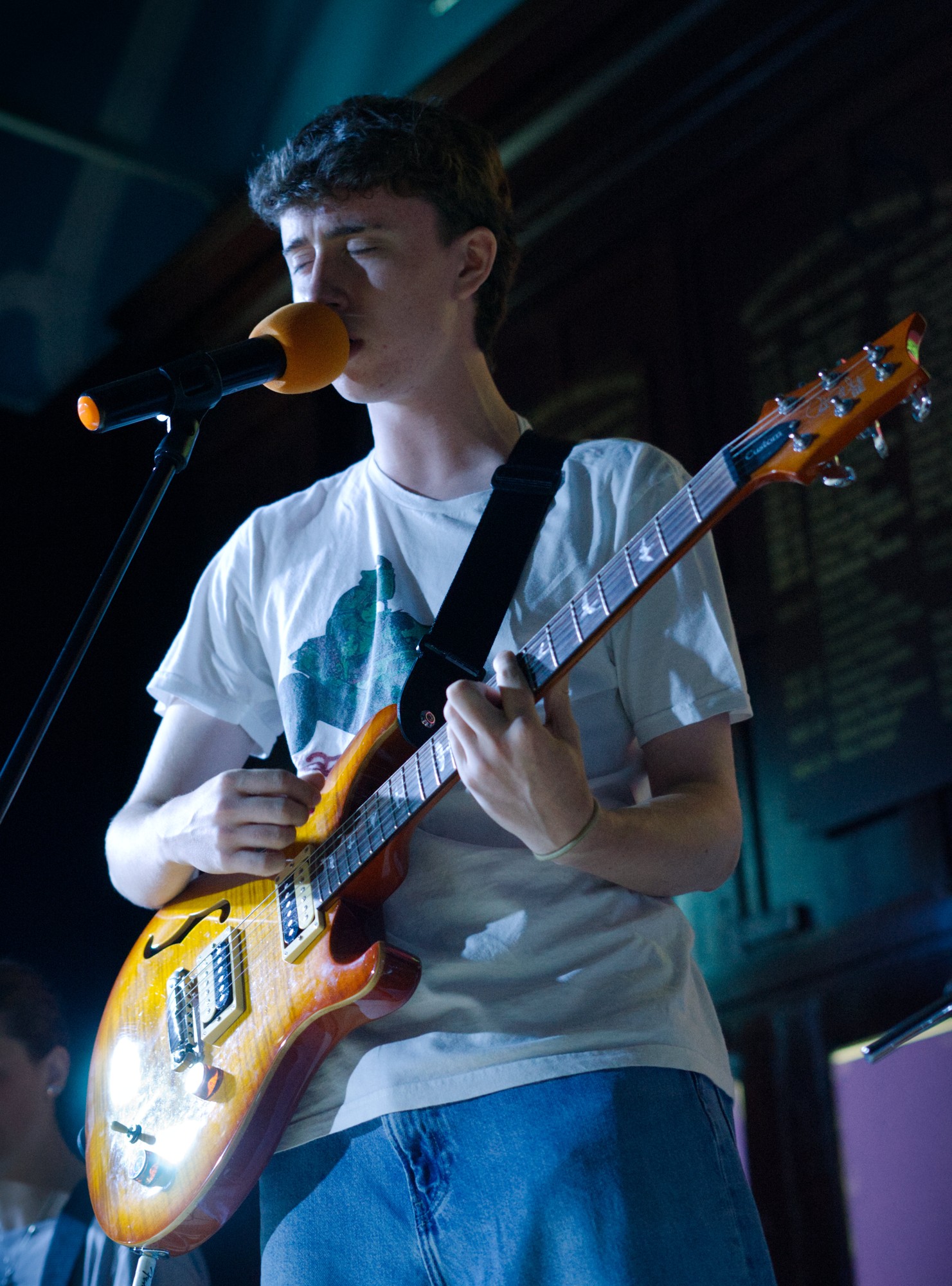 Young musician wearing a guitar strap jumper, ready to play at Rock Now