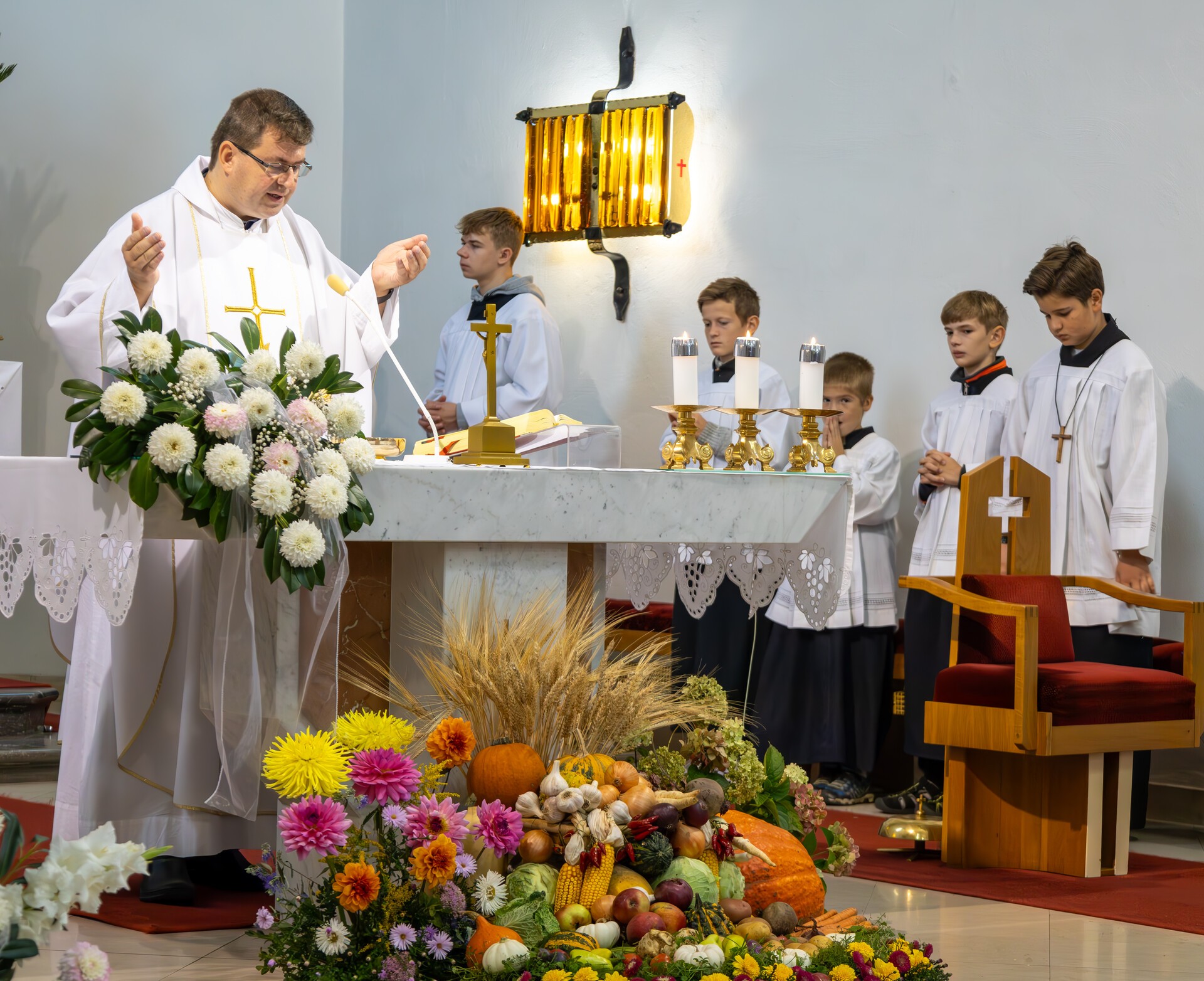 Kněz a ministranti při mši svaté u slavnostně vyzdobeného oltáře
