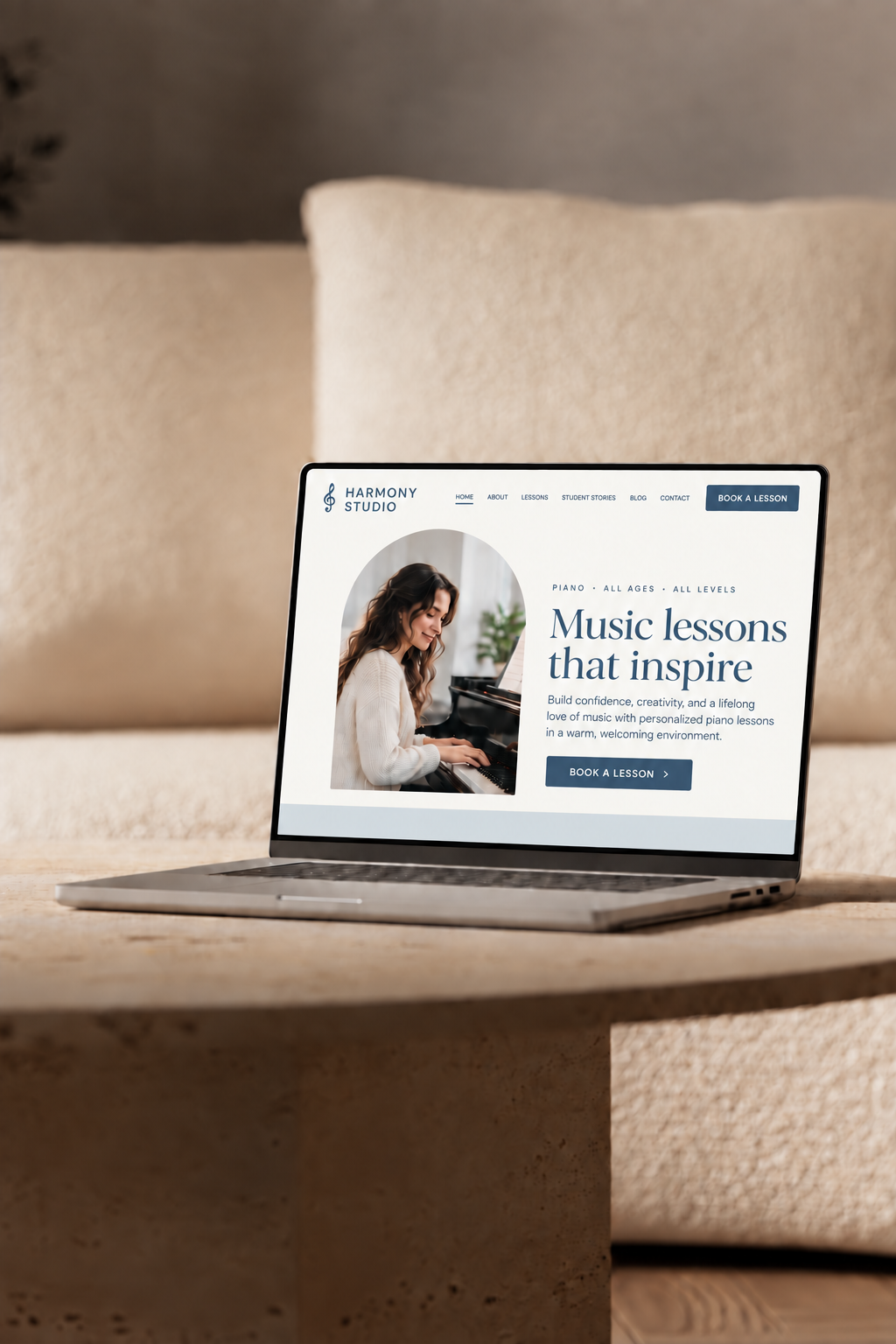 Laptop displaying a piano teacher website in a warm, neutral studio setting