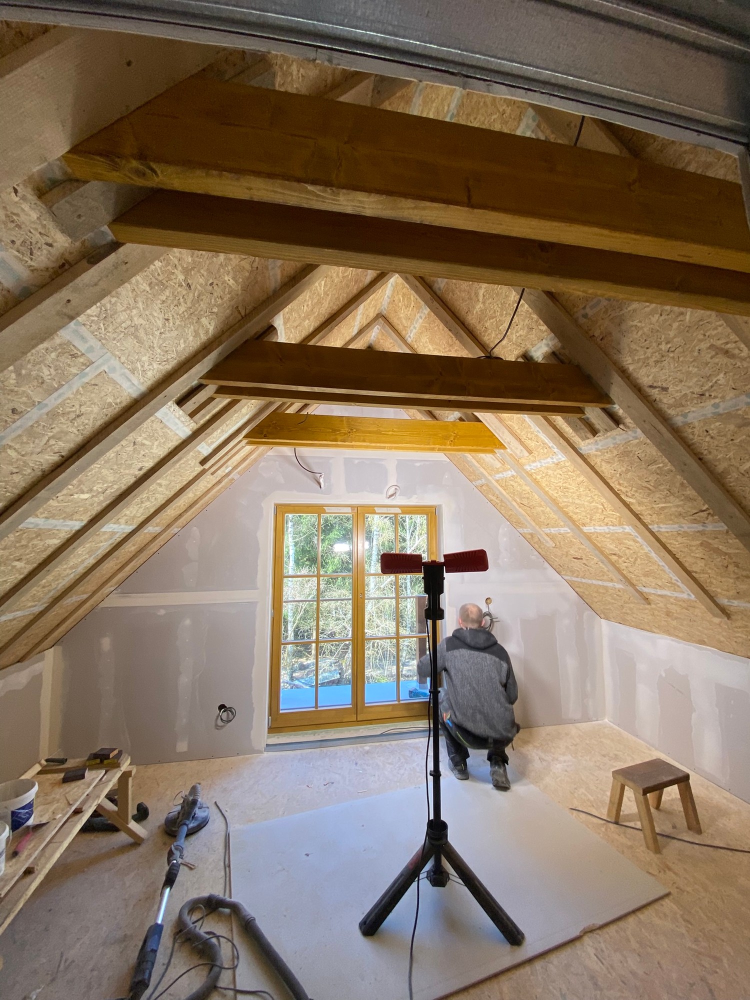 Interiér podkroví během dokončování — přiznané trámy a SDK záklopy