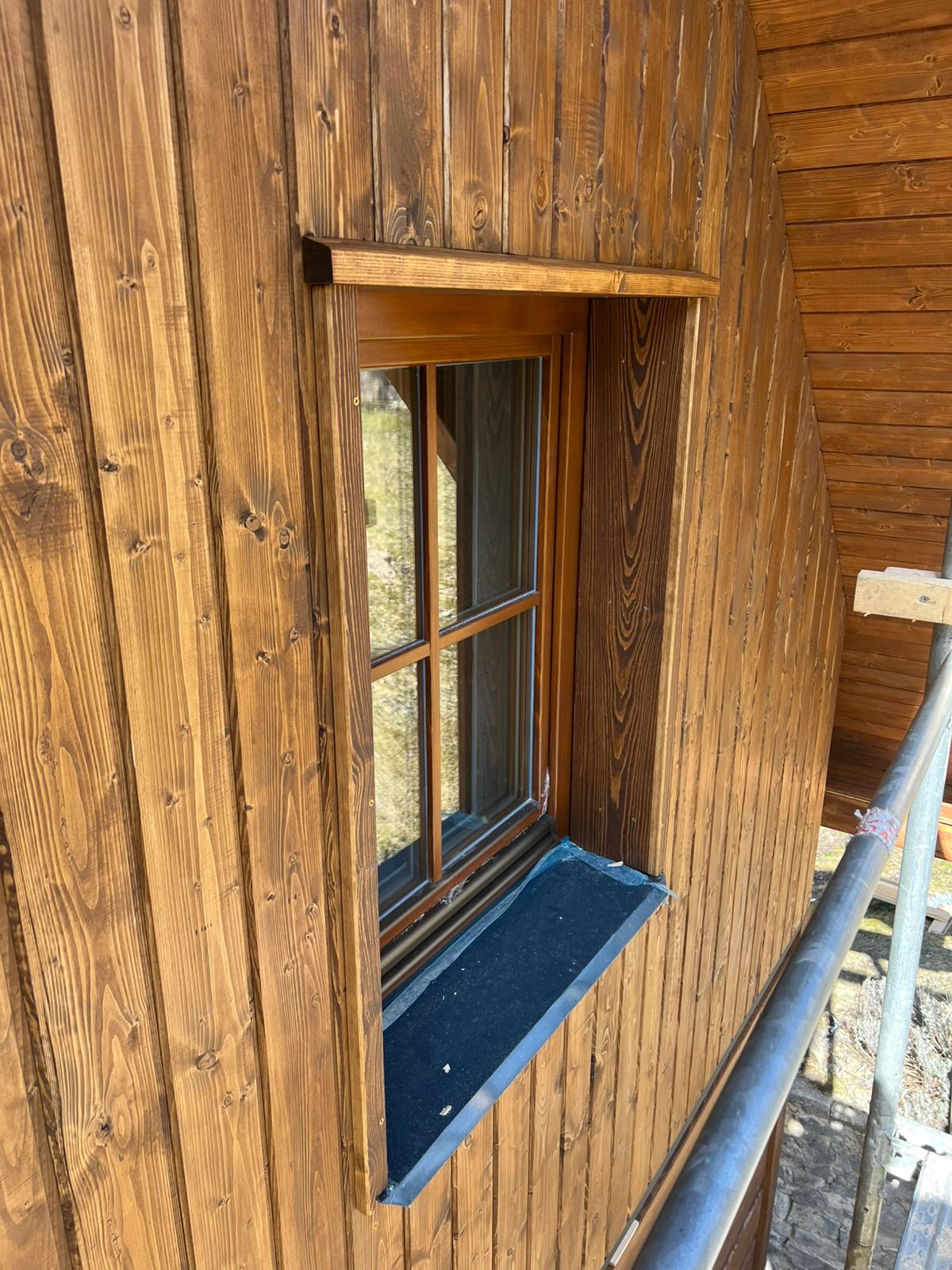 Detail dřevěného eurookna s parapetem na fasádě z falešného roubení