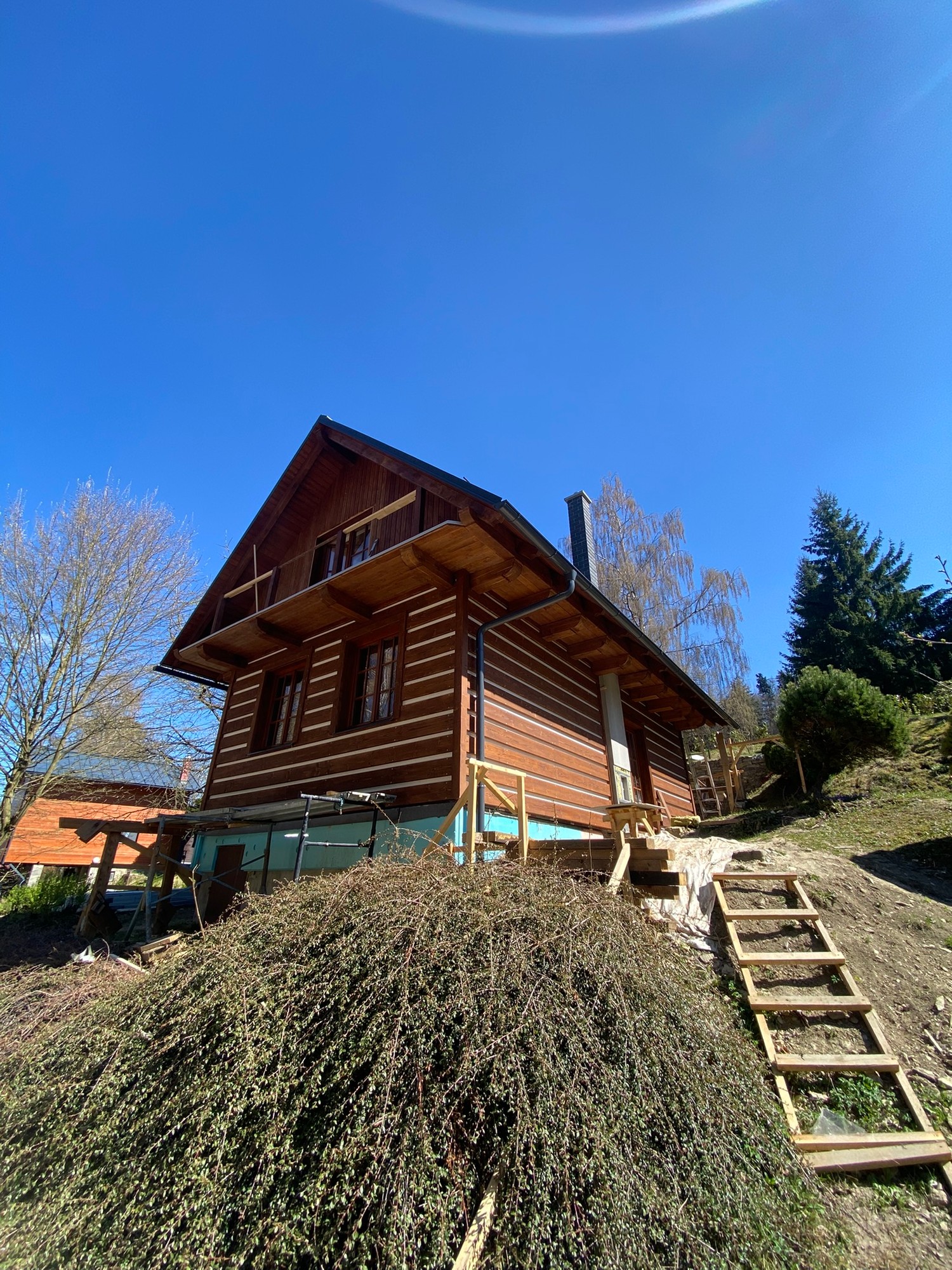 Česká chata — pohled na dokončovaný exteriér s roubením a balkonem