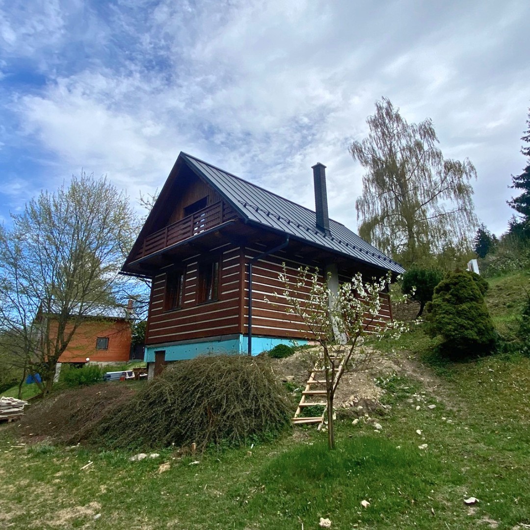 Česká chata — pohled na dokončovaný exteriér s roubením a balkonem