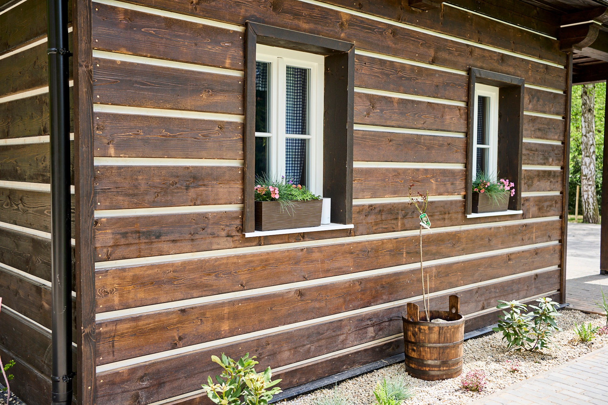 Exteriér dokončené chaty — roubená fasáda z KVH s truhlíky na okně