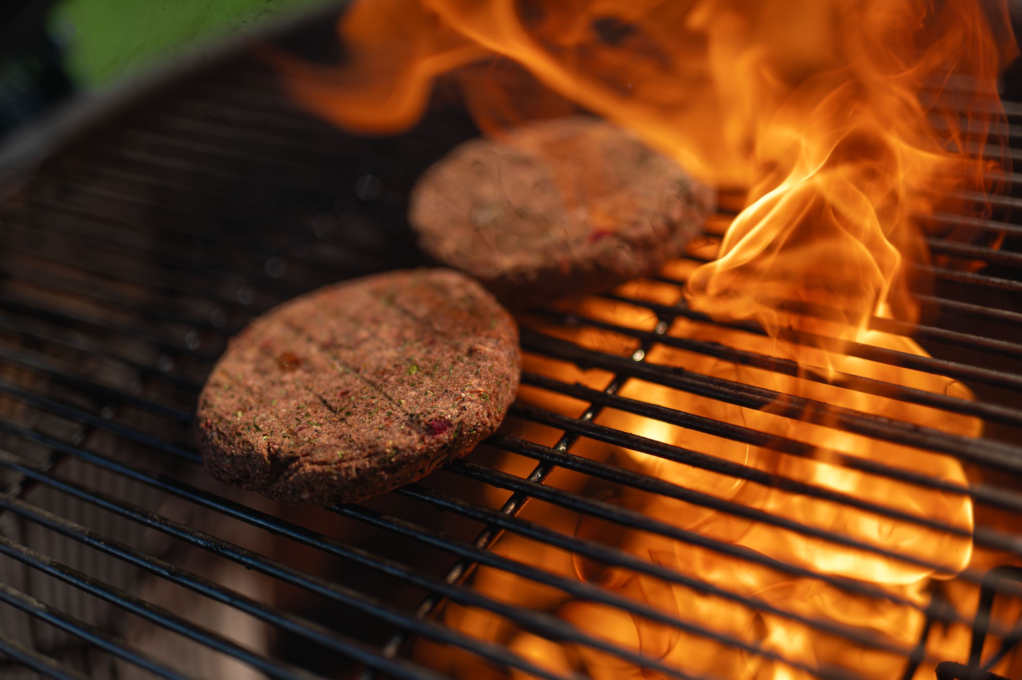 Veggie burger placky na kamado grile v plameňoch — dramatický záber