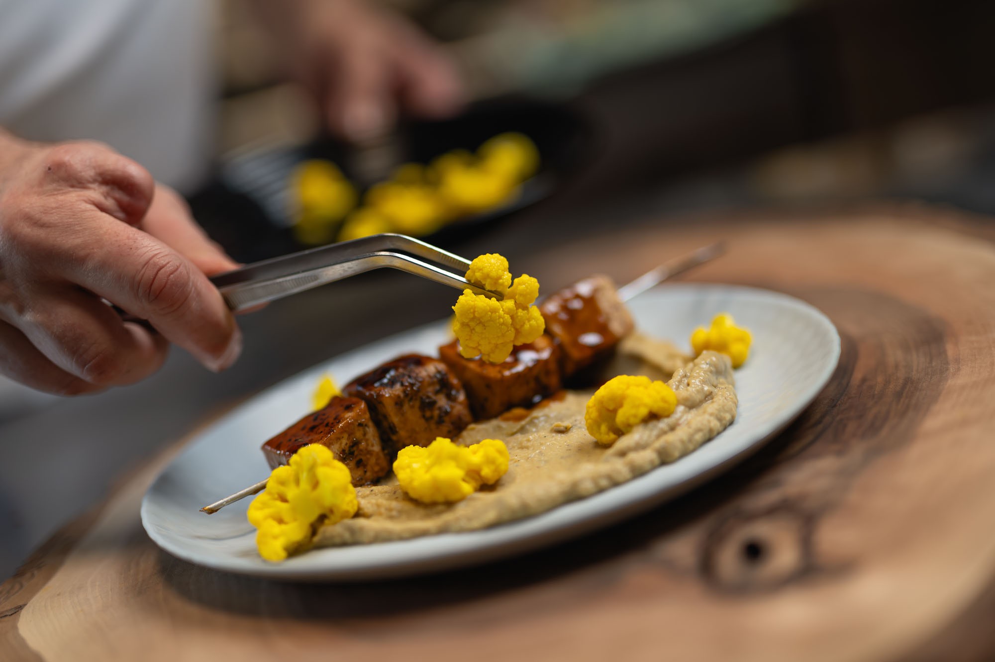 Šéfkuchár servíruje Tofu Spice Šašlík s pinzetou