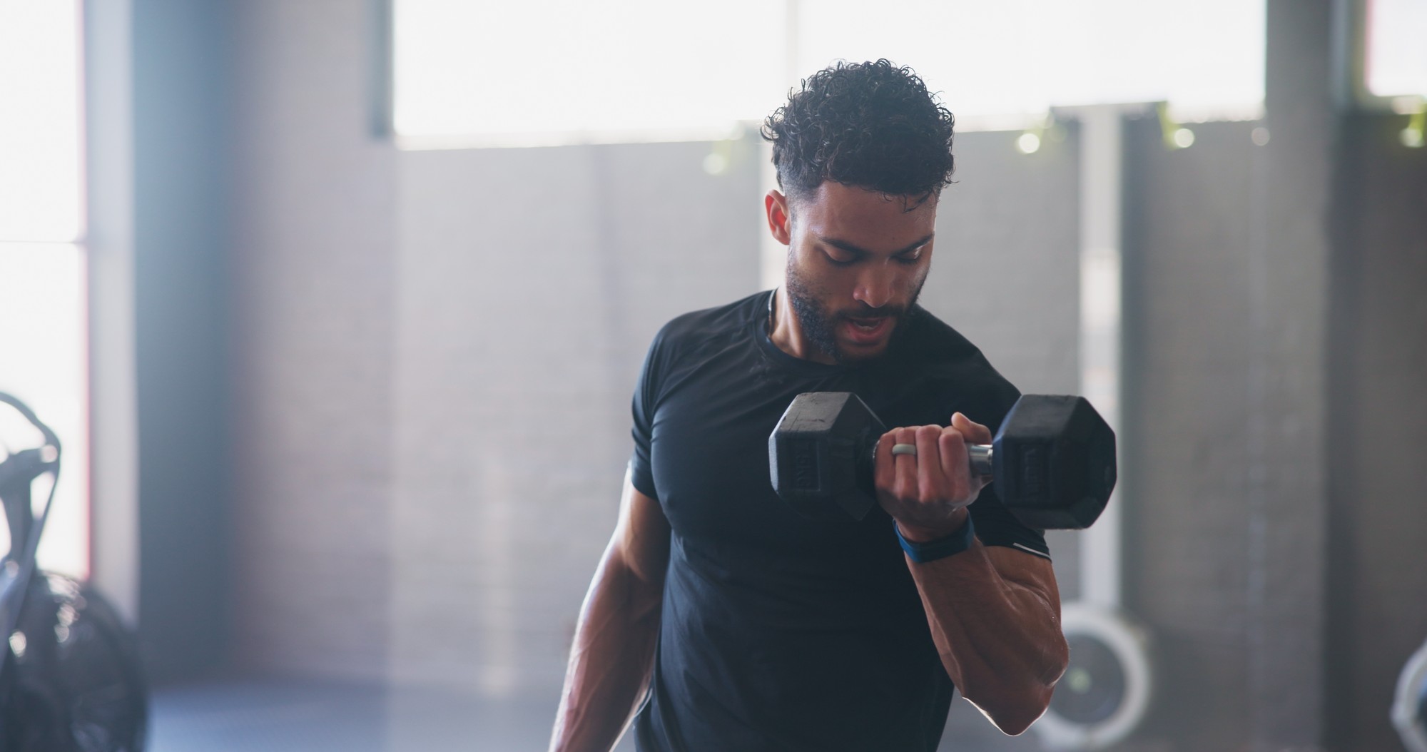 Adult man exercising with a dumbbell in a gym.