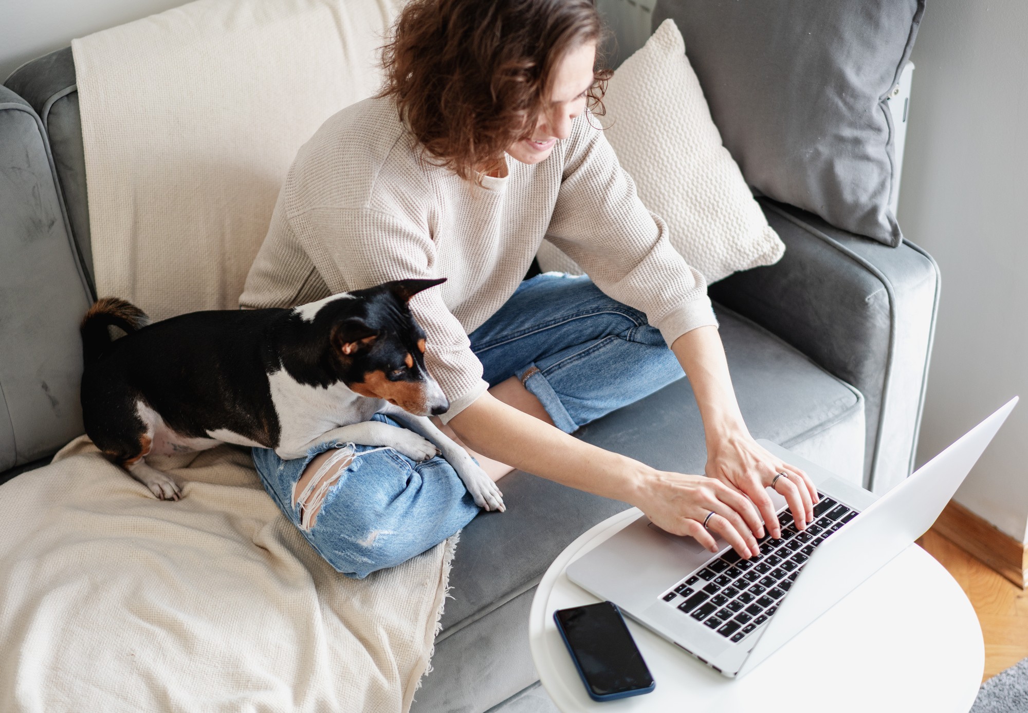 Person sitting on couch with dog while filling out reservation form on laptop