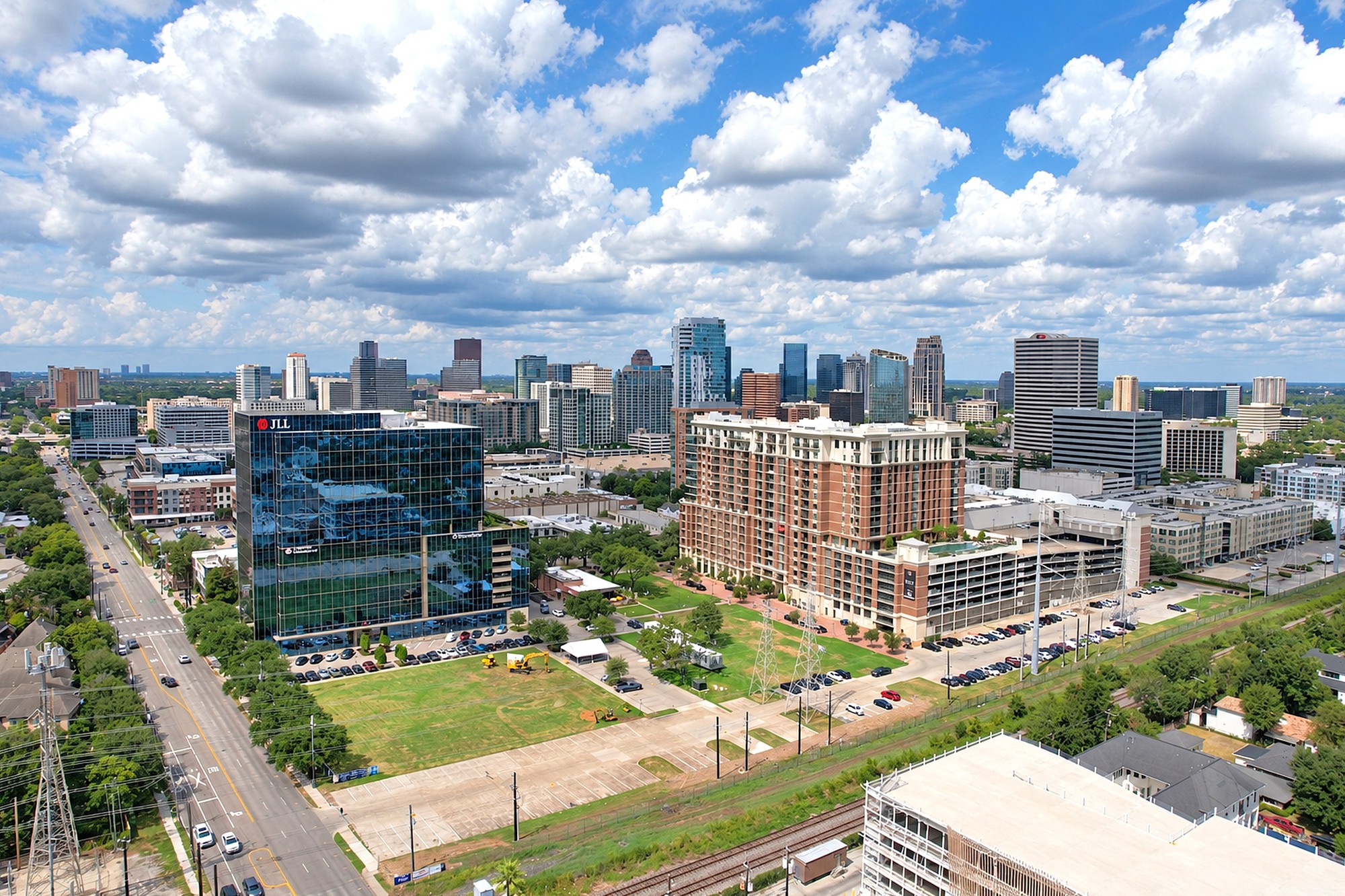 Aerial drone photo of a modern commercial office tower and apartments with the Houston skyline behind