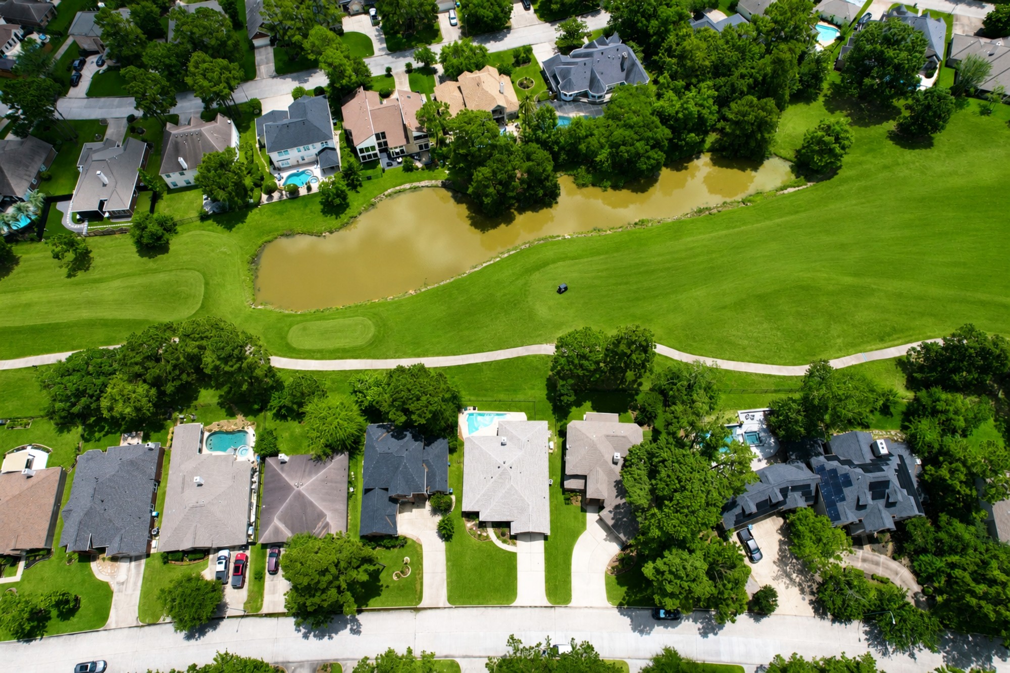 Aerial drone photo of a residential Houston neighborhood with golf course and lake