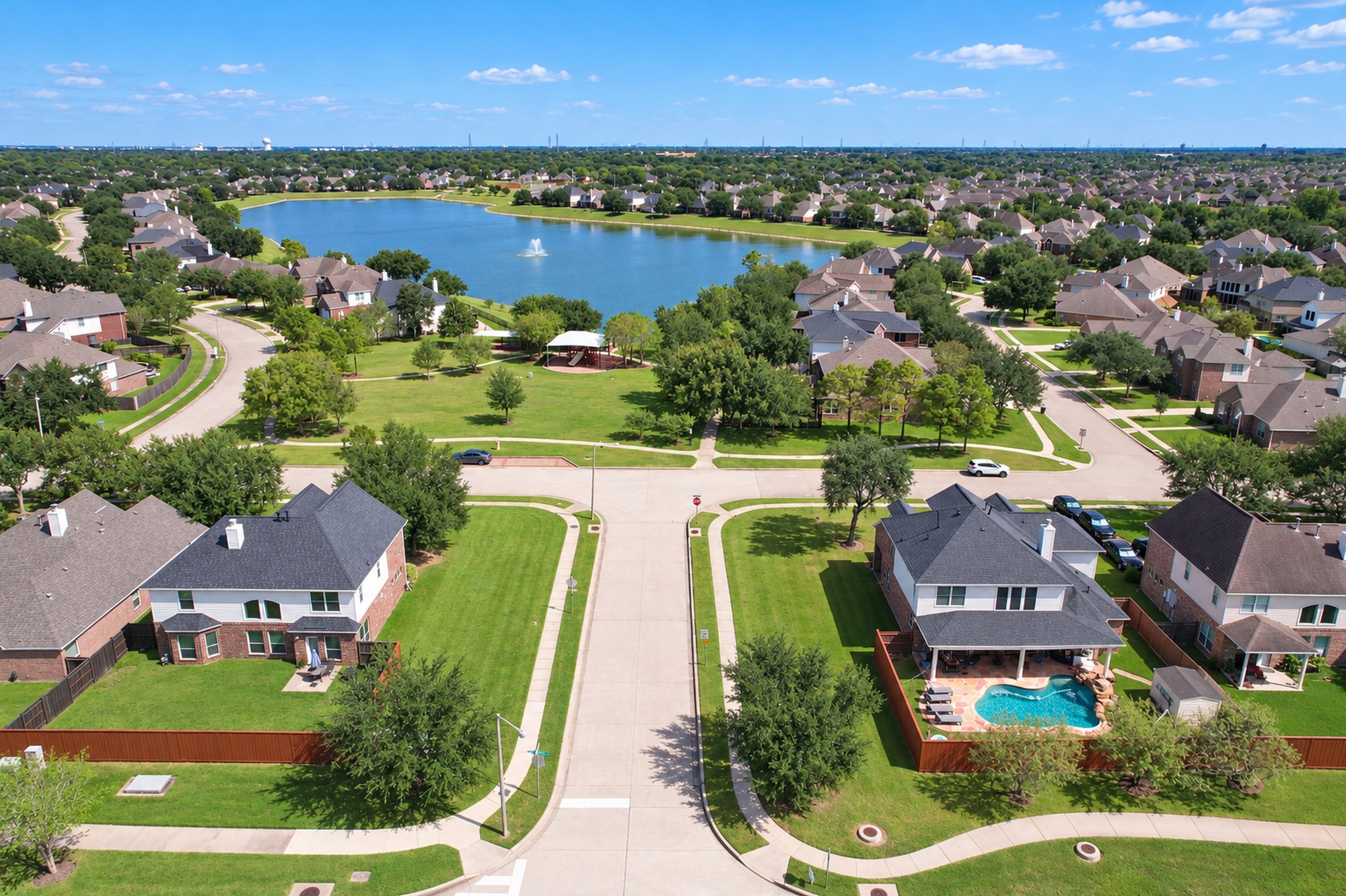 Aerial drone photo of a suburban Houston neighborhood with a community lake and fountain