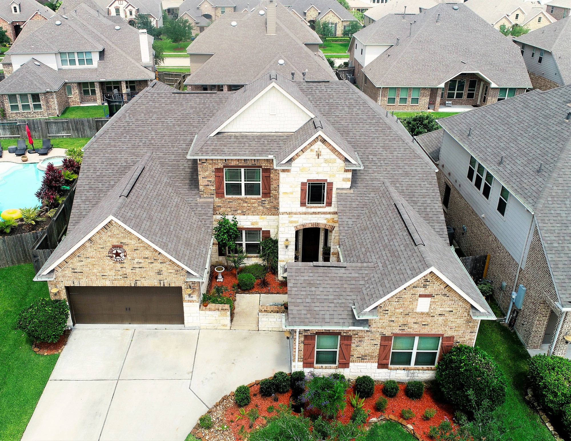 Close aerial drone photo of a brick Houston-area home with pool and landscaping