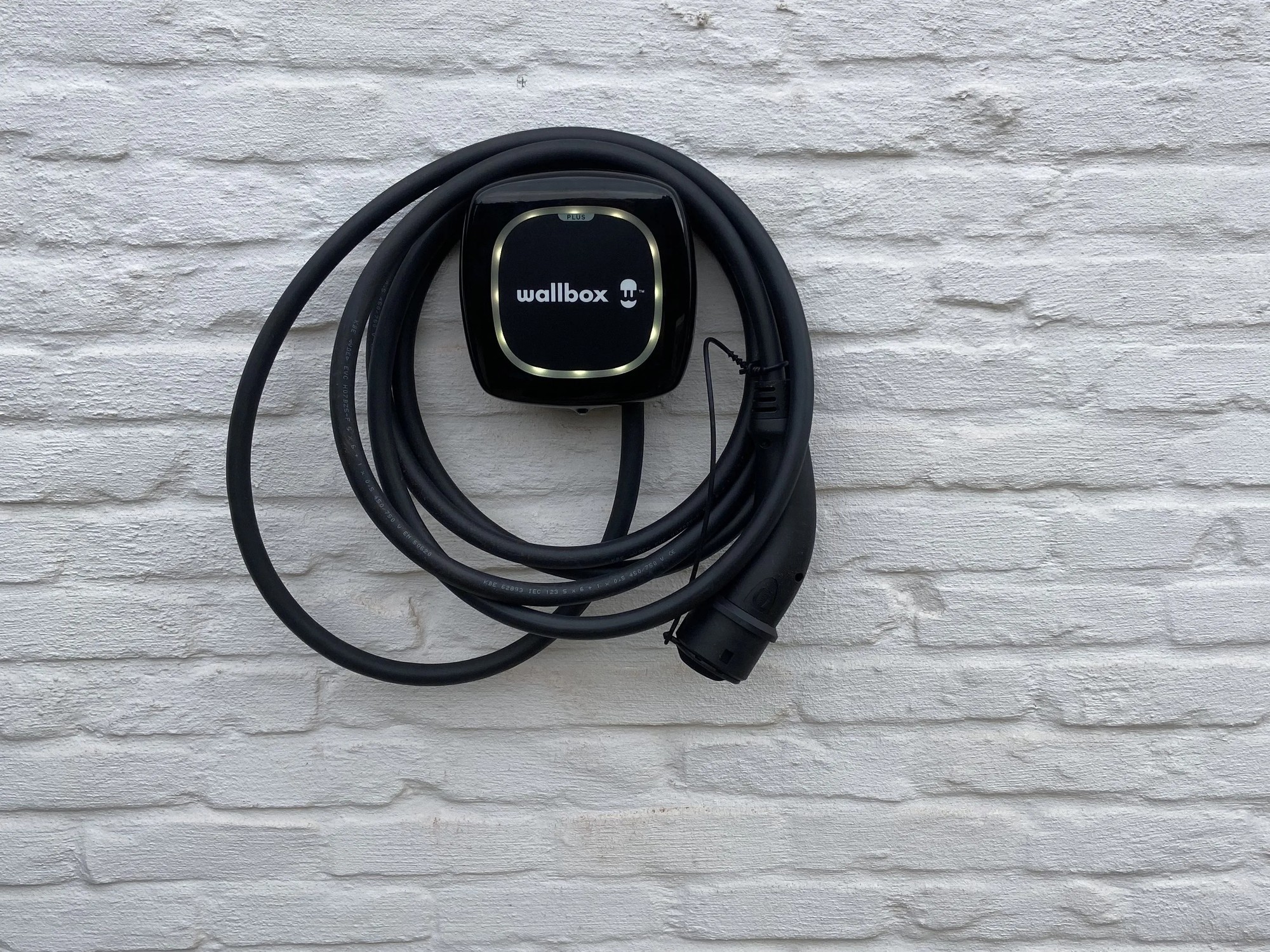 EV-laadpaal (Wallbox) gemonteerd op witte bakstenen muur – installatie door elektricien in Brugge