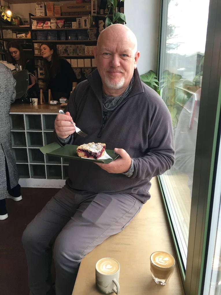 Zákazník si pochutnává na zákusku s latté u okna