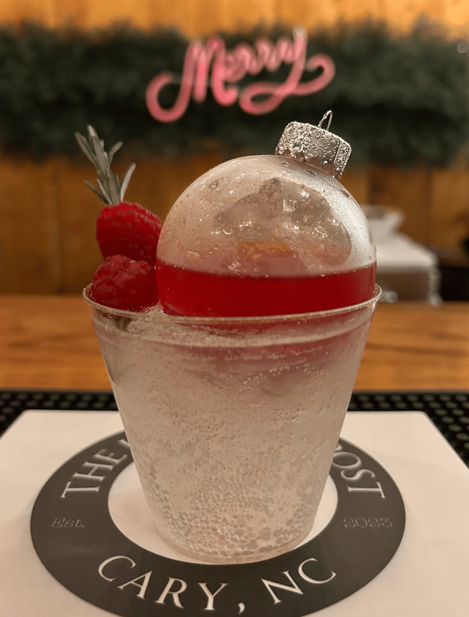 Festive holiday ornament cocktail with raspberries and rosemary served at a corporate holiday party by The Hitching Post