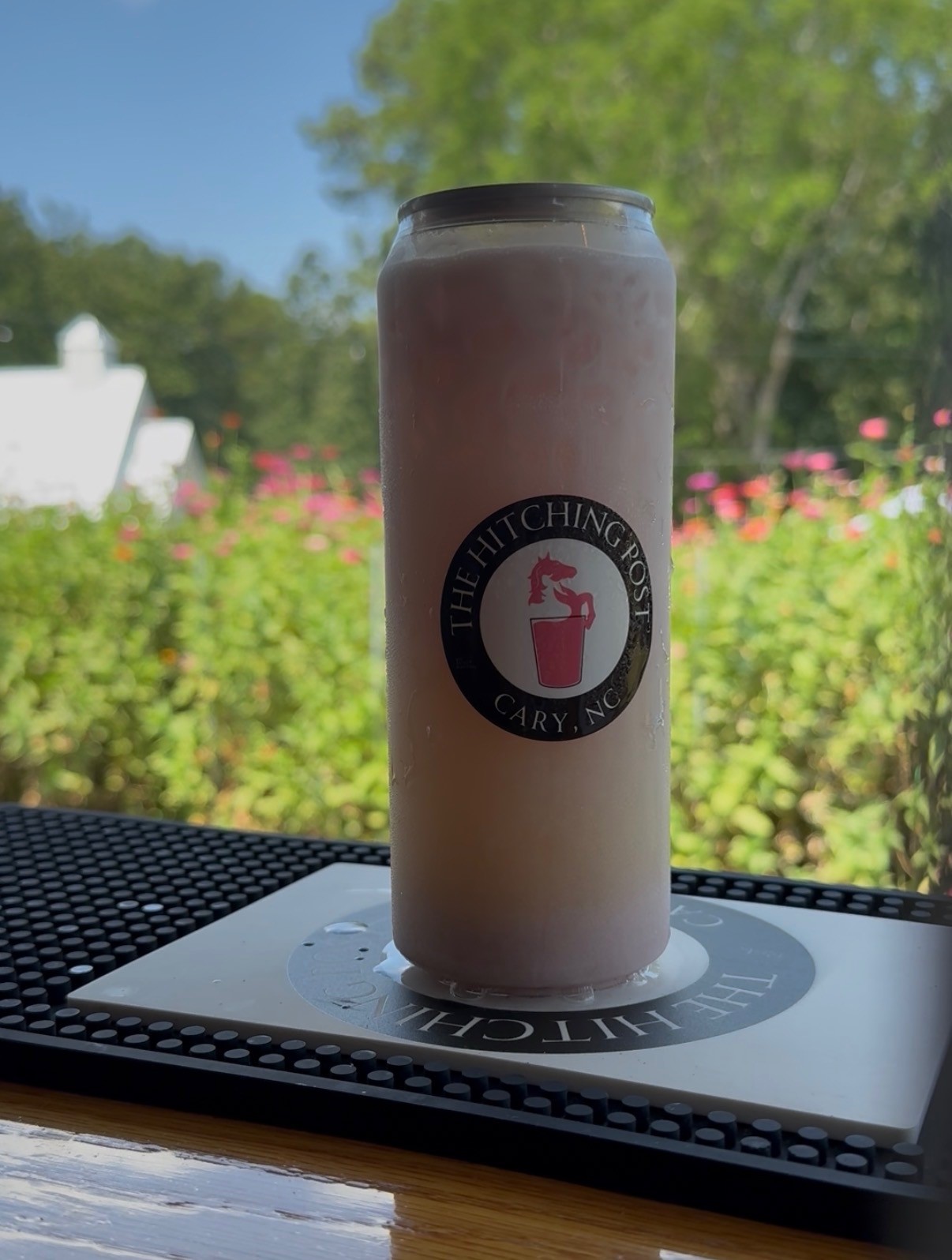 Branded Hitching Post cup on a bar mat with flower garden background — mobile bar Cary NC Raleigh Durham Triangle