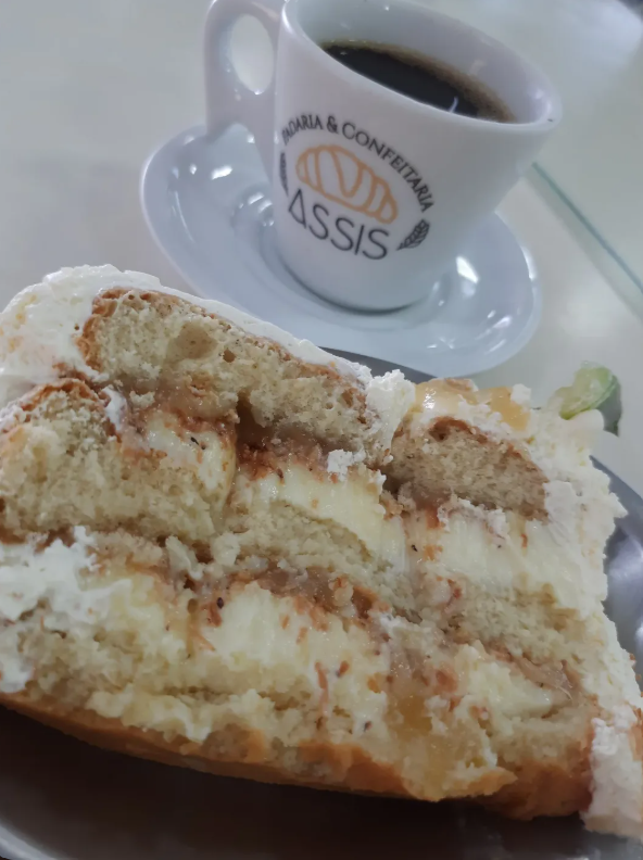 Fatia de bolo servida com café da Padaria Assis