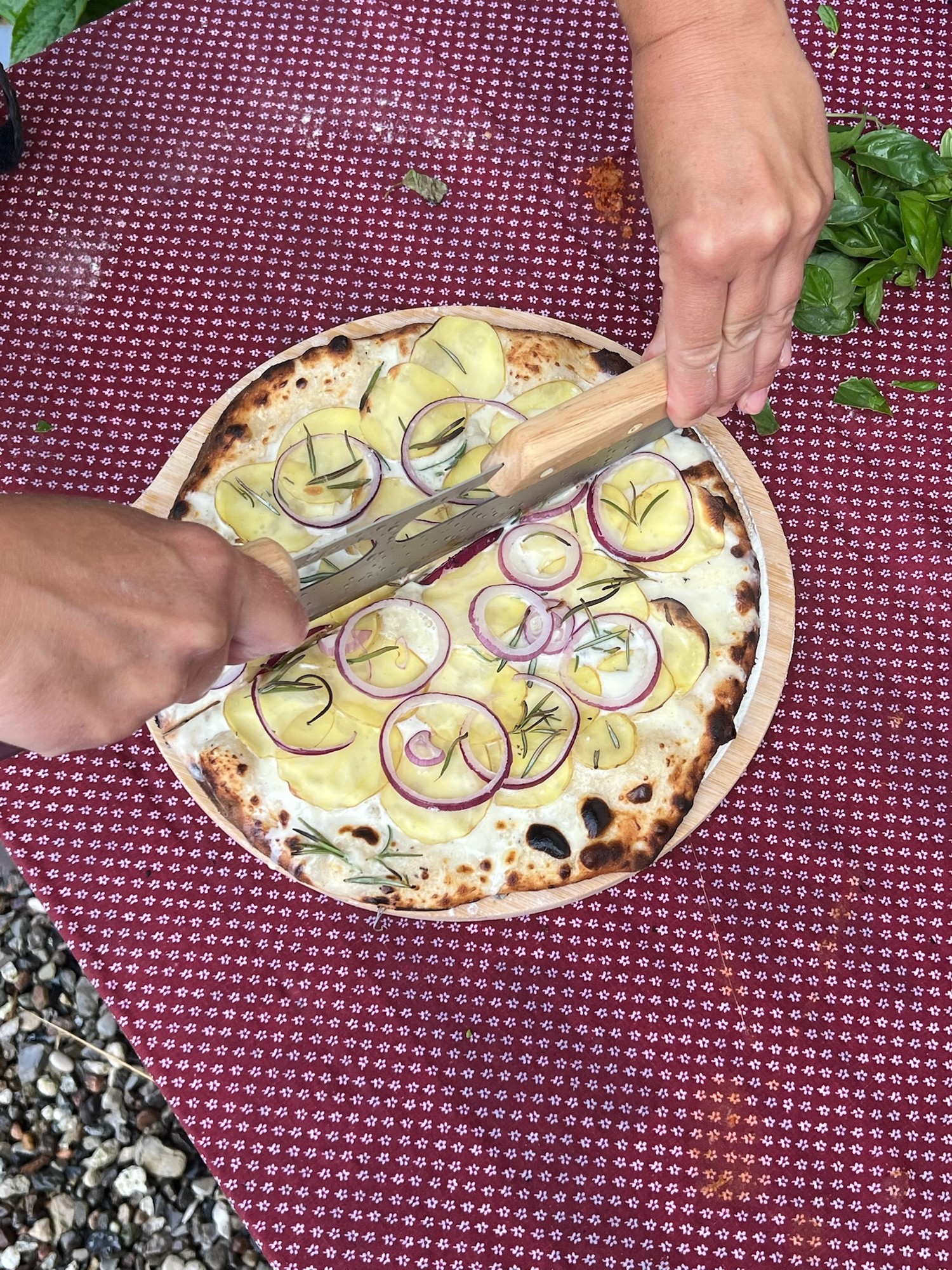 Surdejspizza med kartoffel og rødløg skæres på træbræt